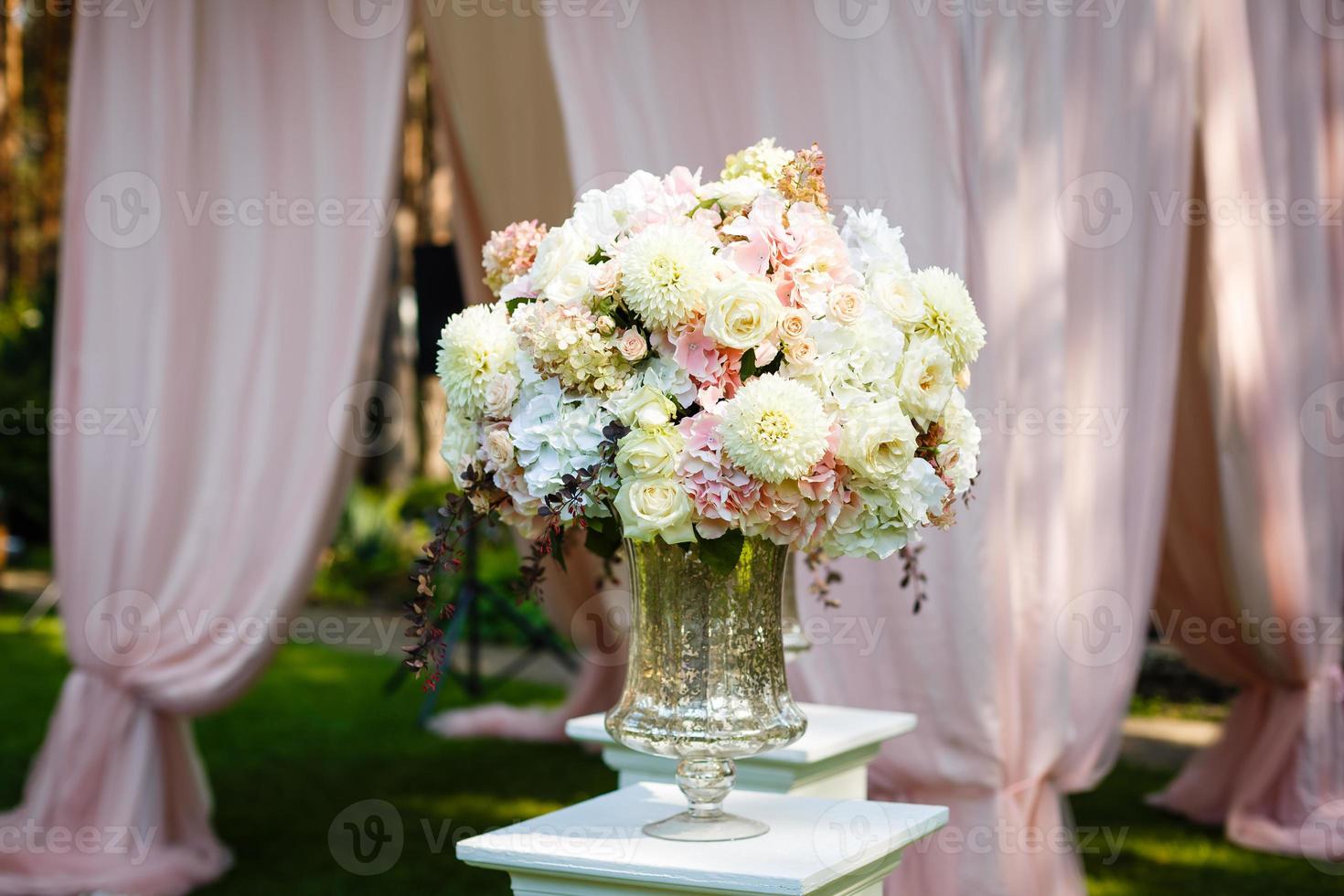 Tall crystal vase with beautiful bouquet of daisies and roses on top photo