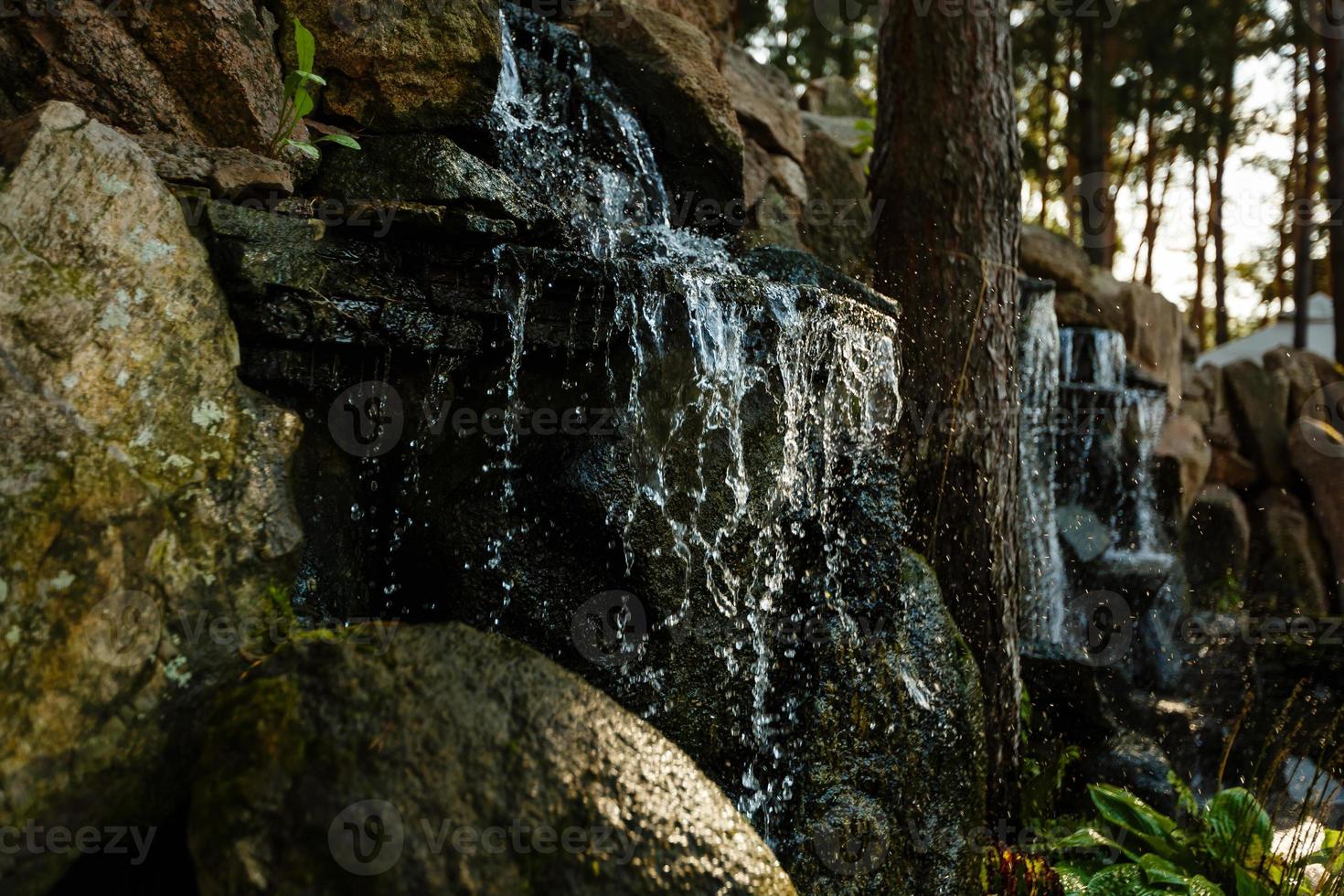 Close up of water splashing on rocks from a waterfall Water on decorative stones photo