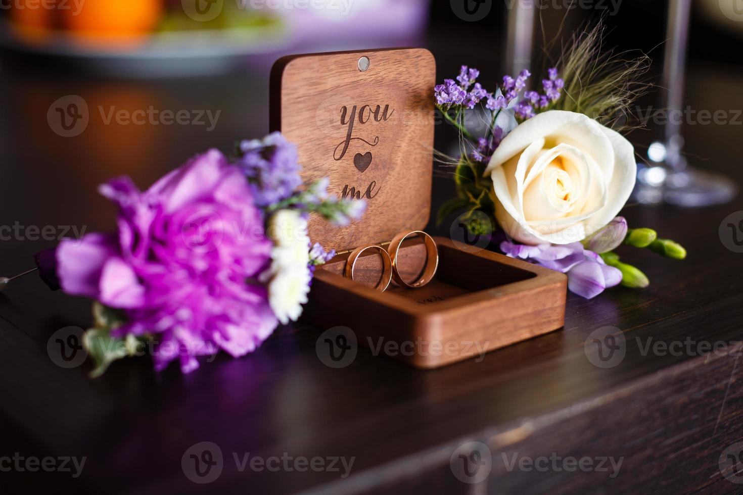 Wedding boutonniere. Gold rings lay in a wooden box. Purple white composition. photo