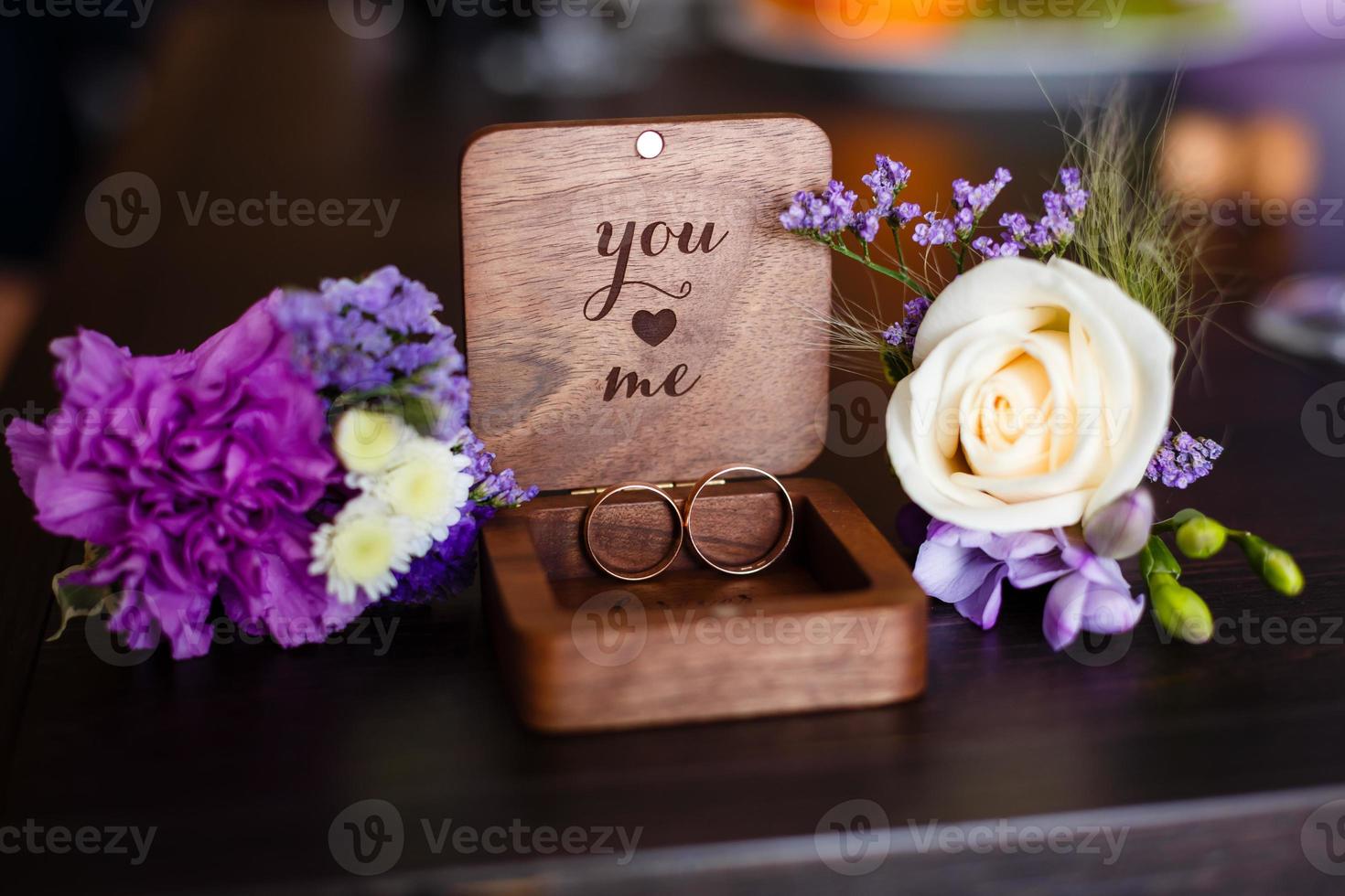 Wedding boutonniere. Gold rings lay in a wooden box. Purple white composition. photo