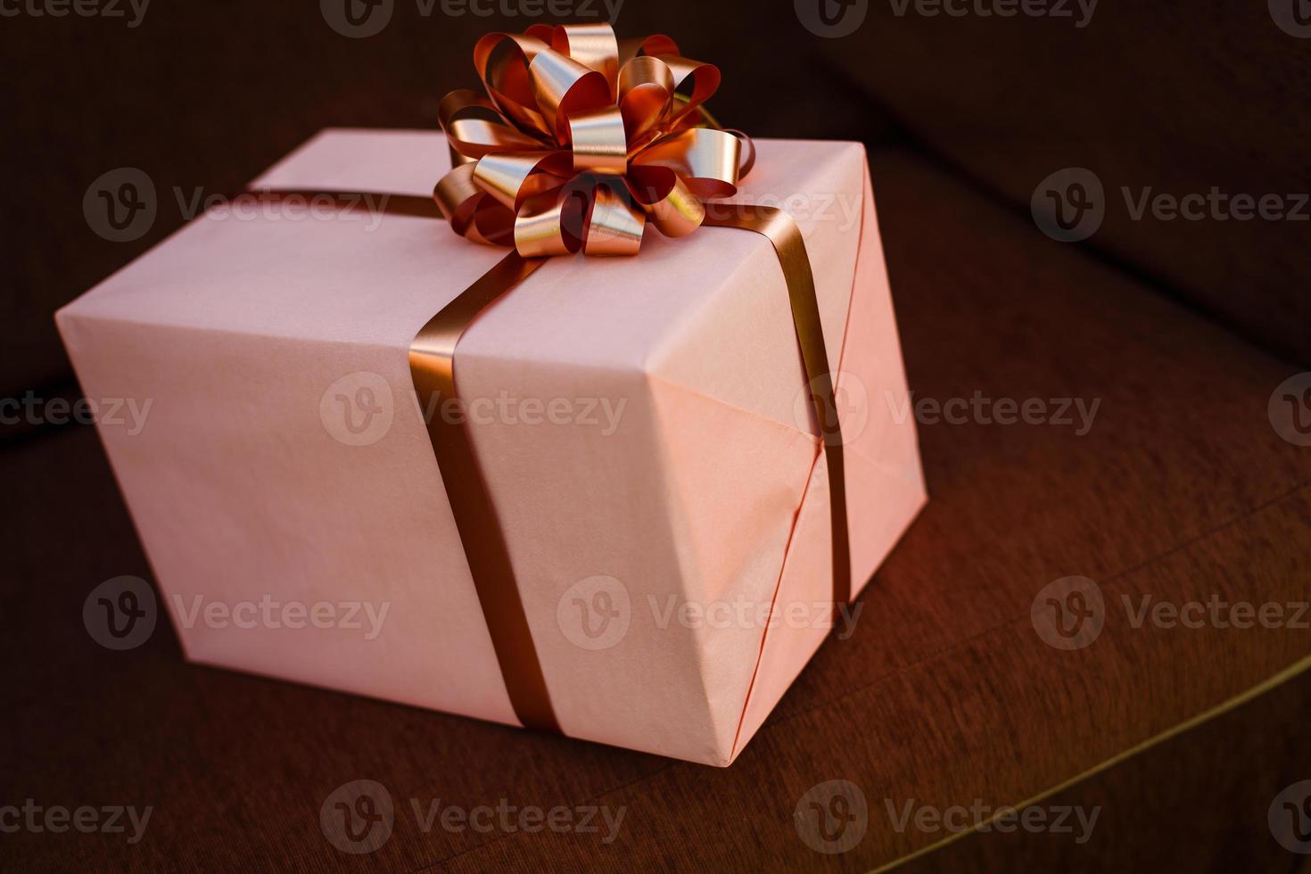 Handmade pink gift box with blue ribbon and bow on the wood old table. photo