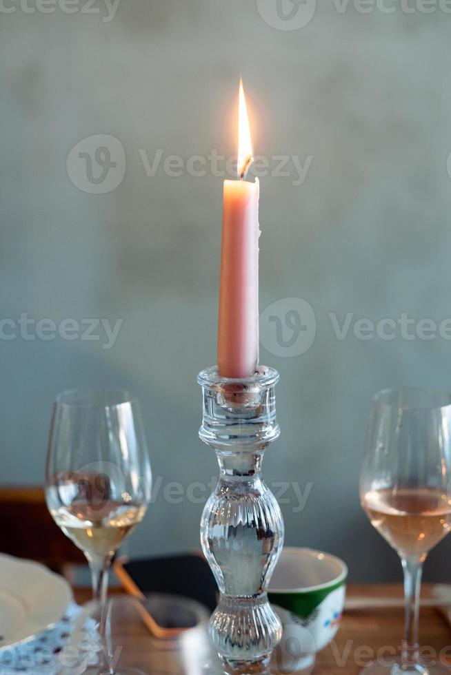 pink candle in a candelabra on a table close-up with glasses of wine and champagne photo