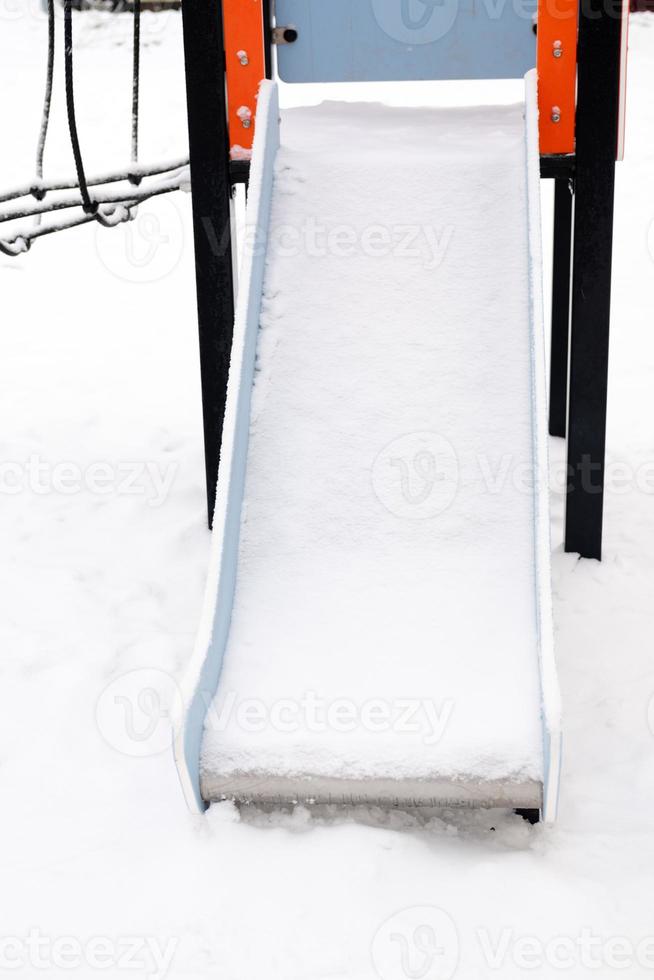 snow-covered empty slide on the street, on the playground photo