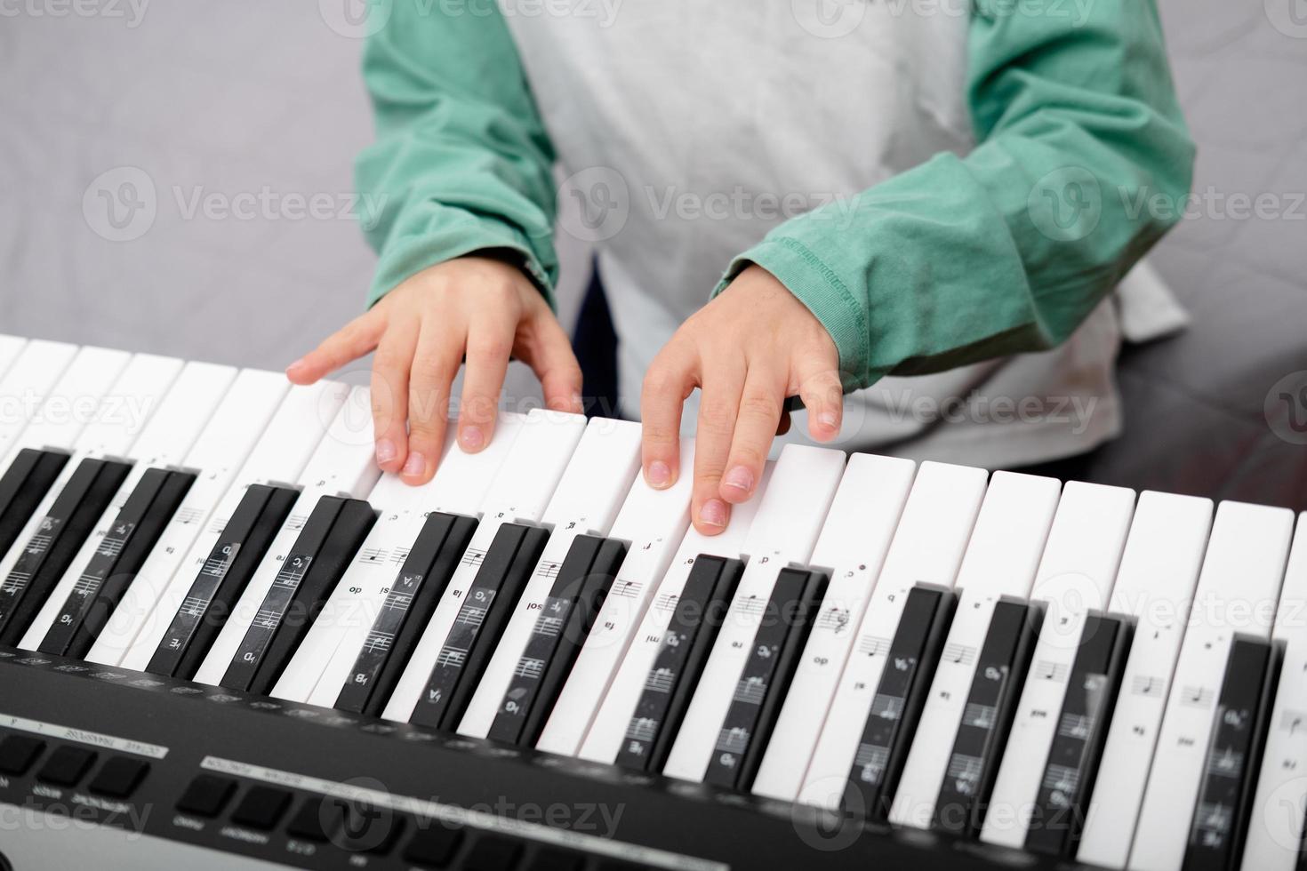 boy's hands over the synthesizer, close-up, top view photo