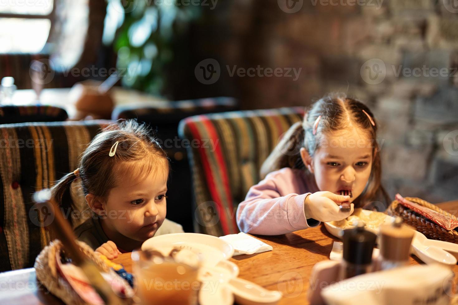 Family having a meal together in authentic ukrainian restaurant. Girls children eat dumplings. photo