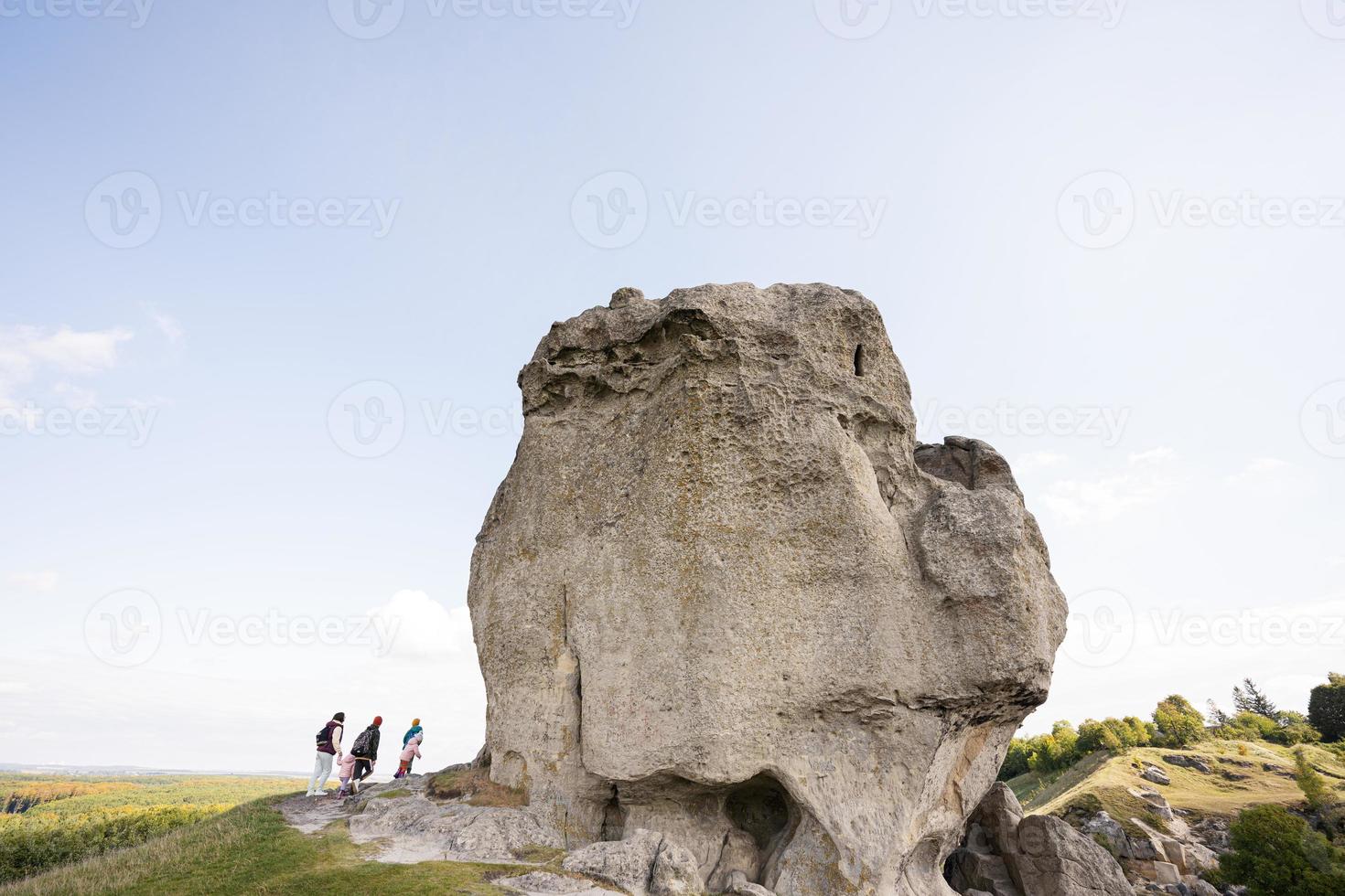 Kids exploring nature. Children wear backpack hiking with mother near big stone in hill. Pidkamin, Ukraine. photo