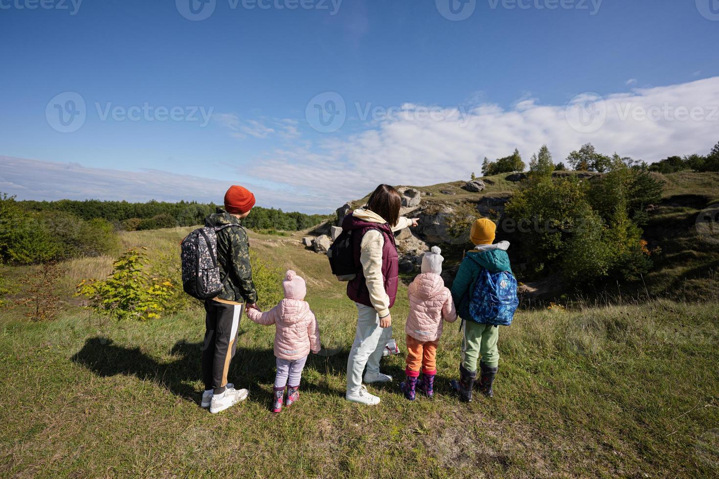 Activity on sunny autumn day, kids exploring nature. Children wear backpack hiking with mother. photo