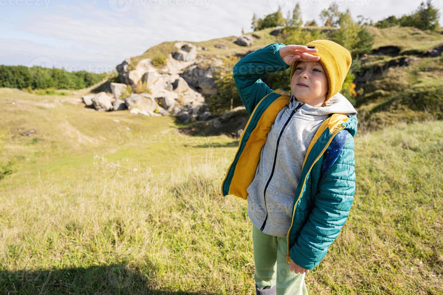 actividad en el soleado día de otoño, niño explorando la naturaleza. niño use sombrero amarillo y mochila de senderismo. foto
