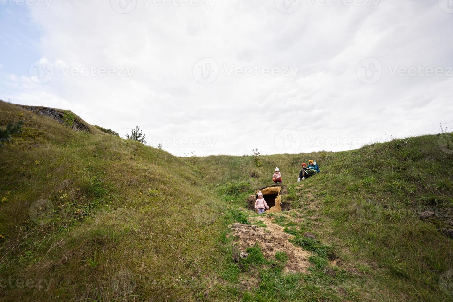 Four kids explore limestone stone cave at mountain. photo