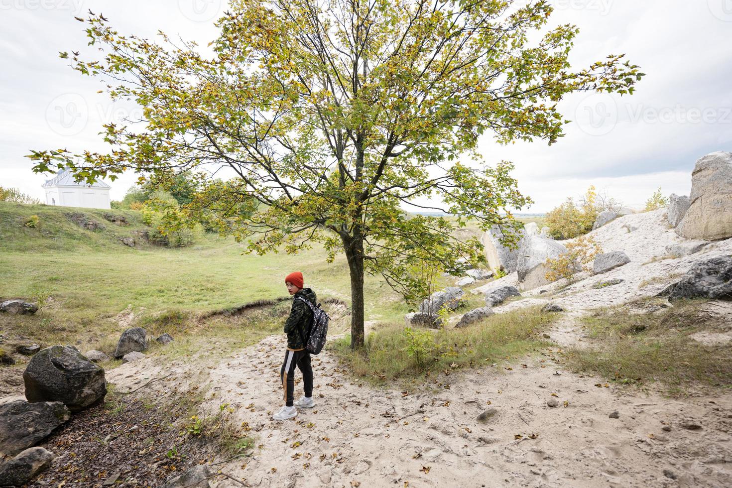 Boy wear backpack explore limestone stone cave at mountain in Pidkamin, Ukraine. photo