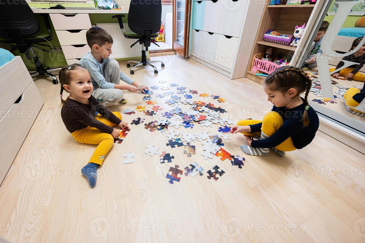 niños conectando piezas de rompecabezas en una habitación para niños en el piso en casa. diversión actividad familiar ocio. foto