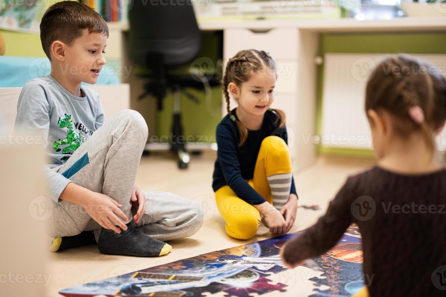 Children connecting jigsaw puzzle pieces in a kids room on floor at home.  Fun family activity leisure. photo
