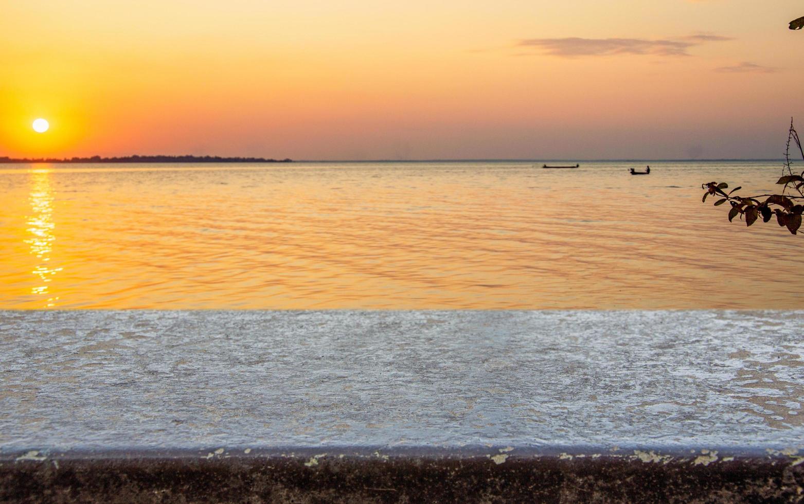 Stone shelf in the backdrop of sunset sea  Free space for product presentation photo