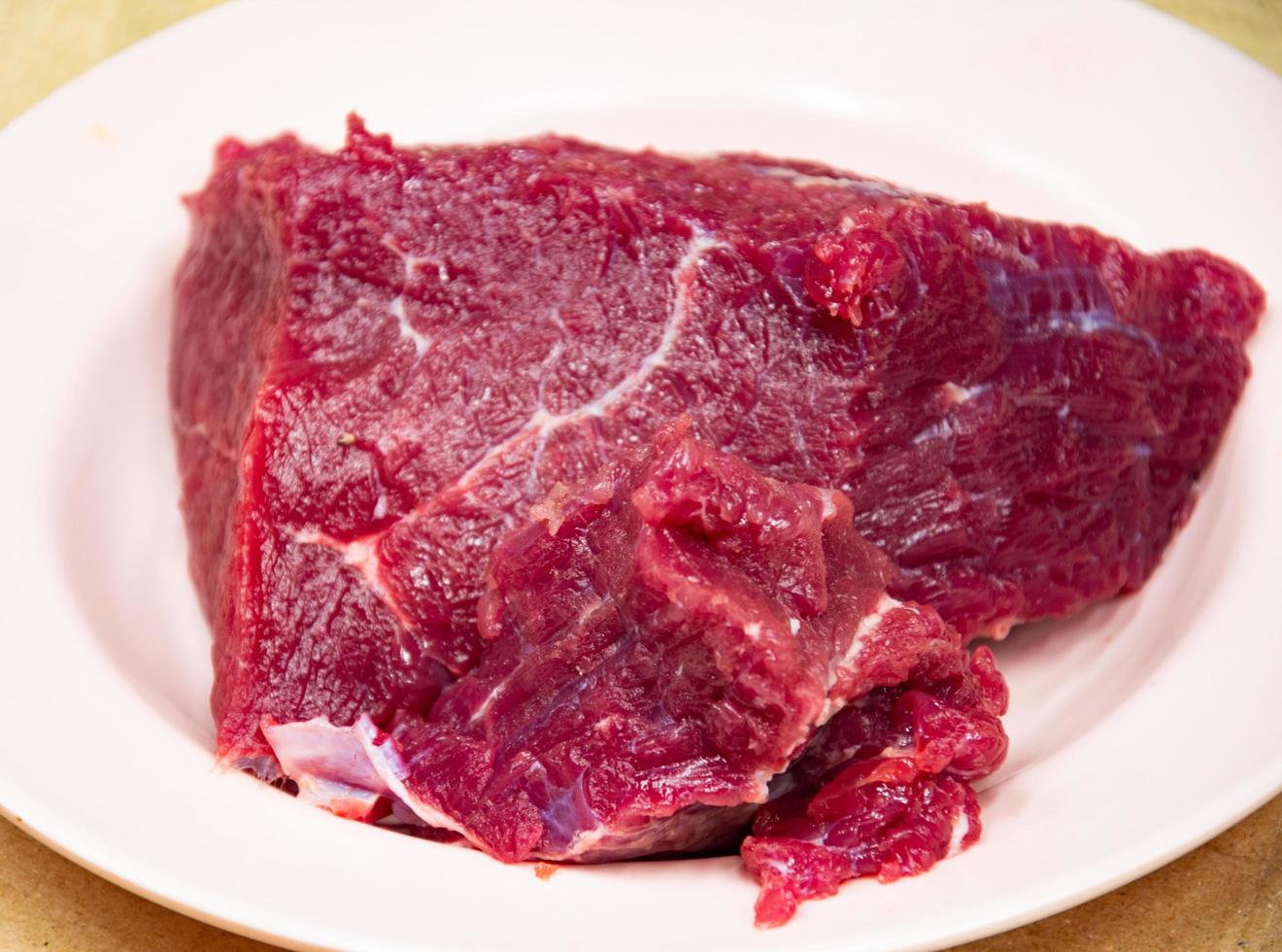 grandes trozos de carne roja fresca en un plato blanco. matadero. carnicería. Cerdo. foto