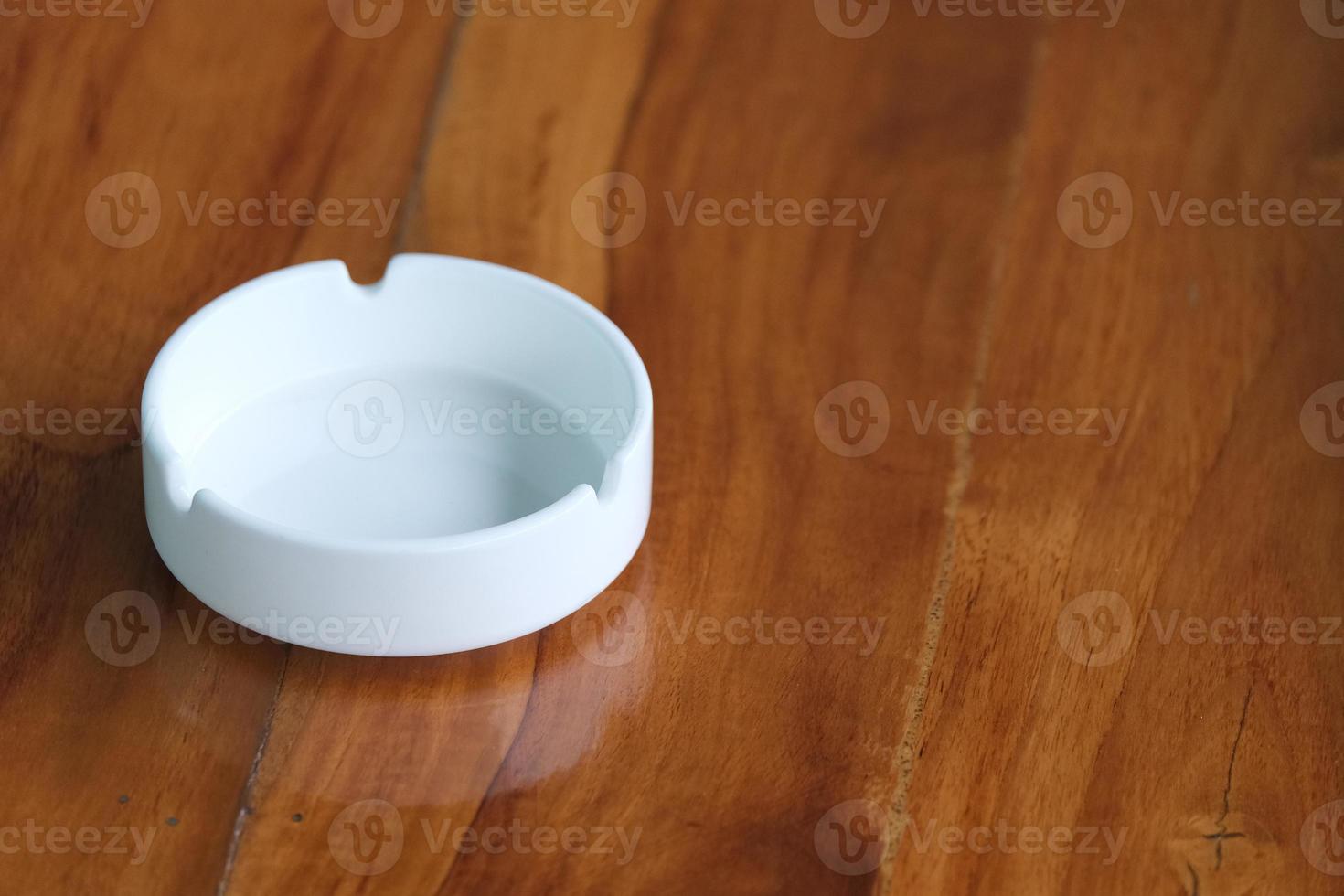 White ashtray on brown wooden table photo