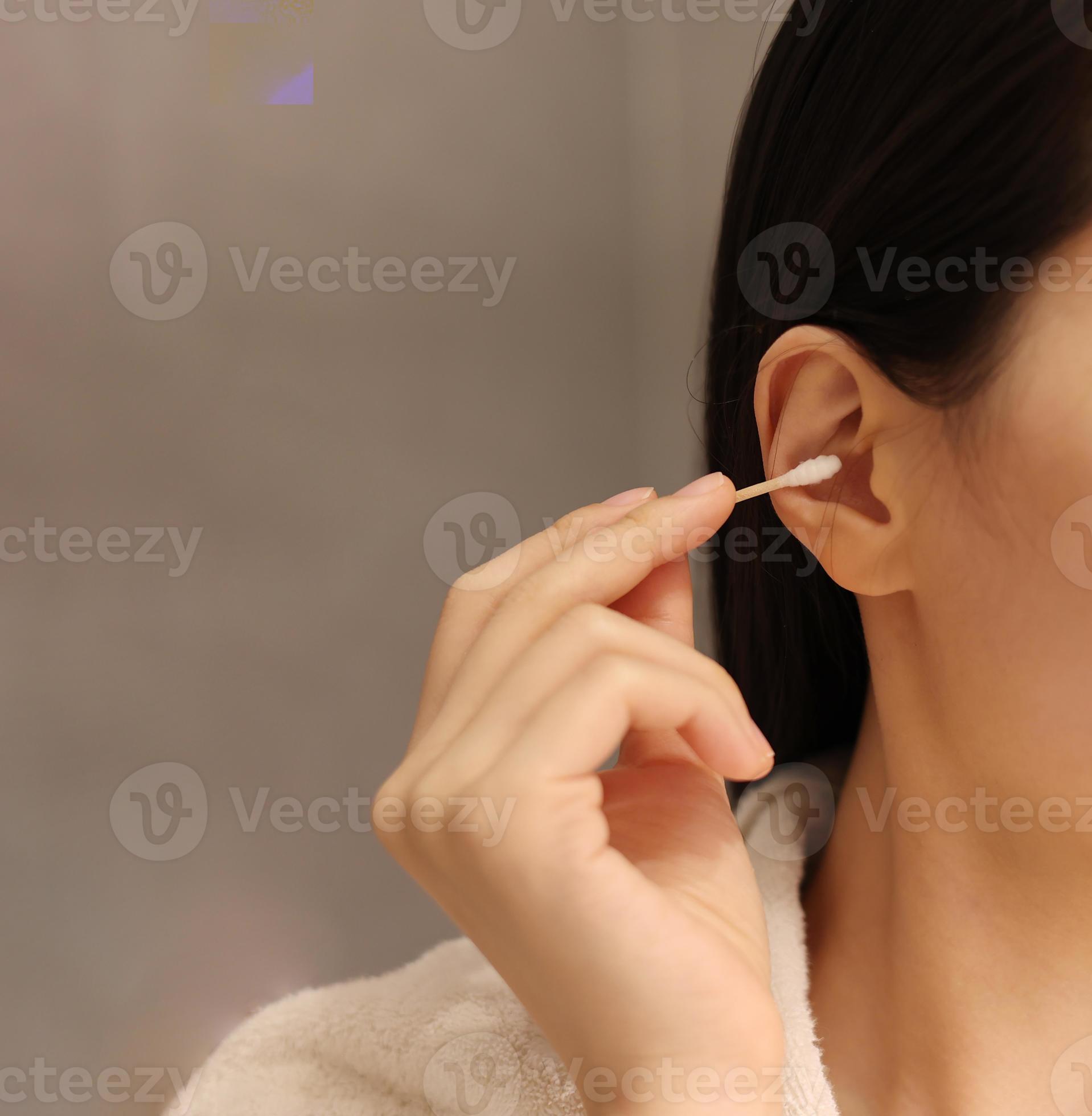 Woman cleaning her ear with a cotton swab after taking a shower