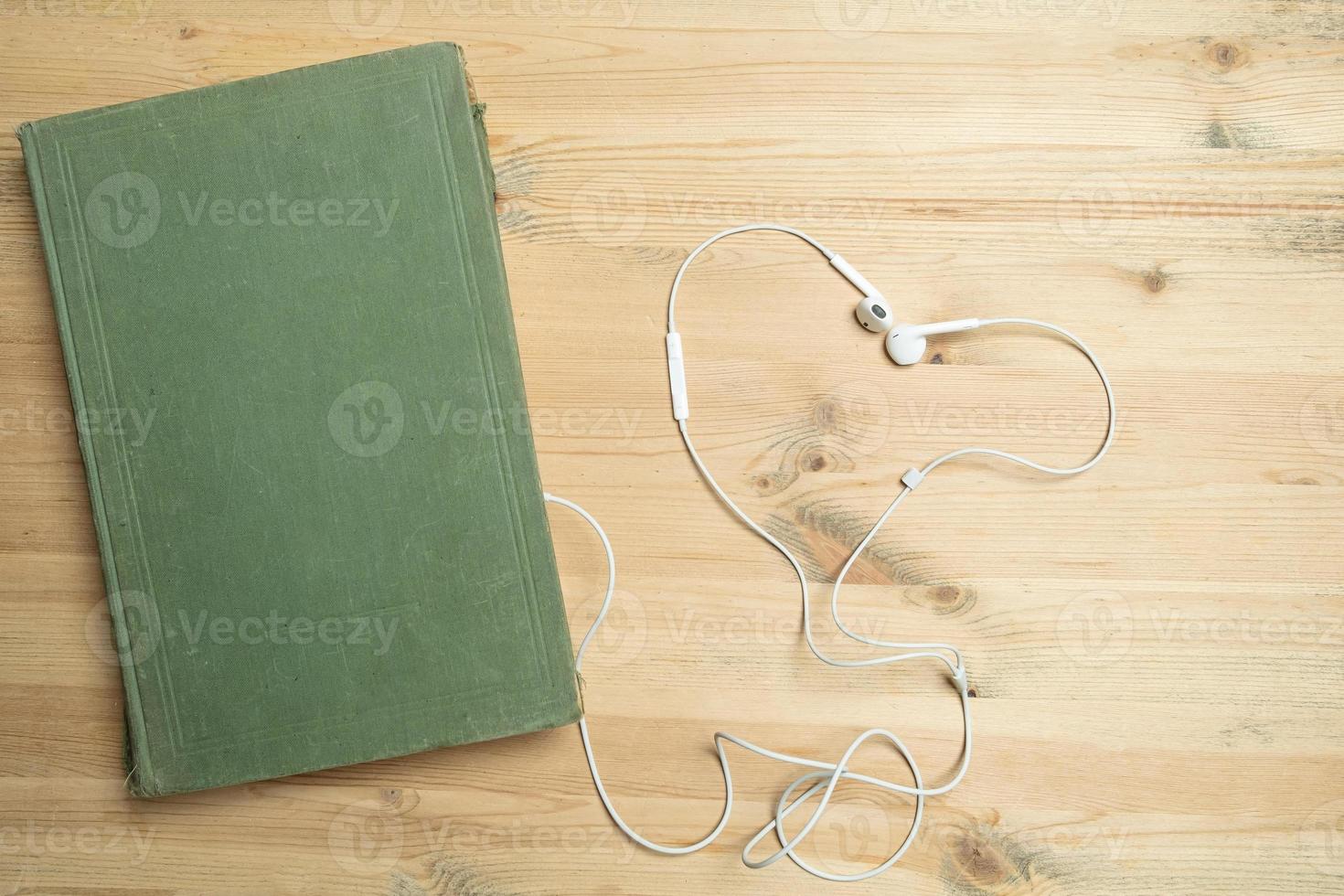 Book and headphones on a wooden table. Audiobook concept. Flatley. Copy space. photo