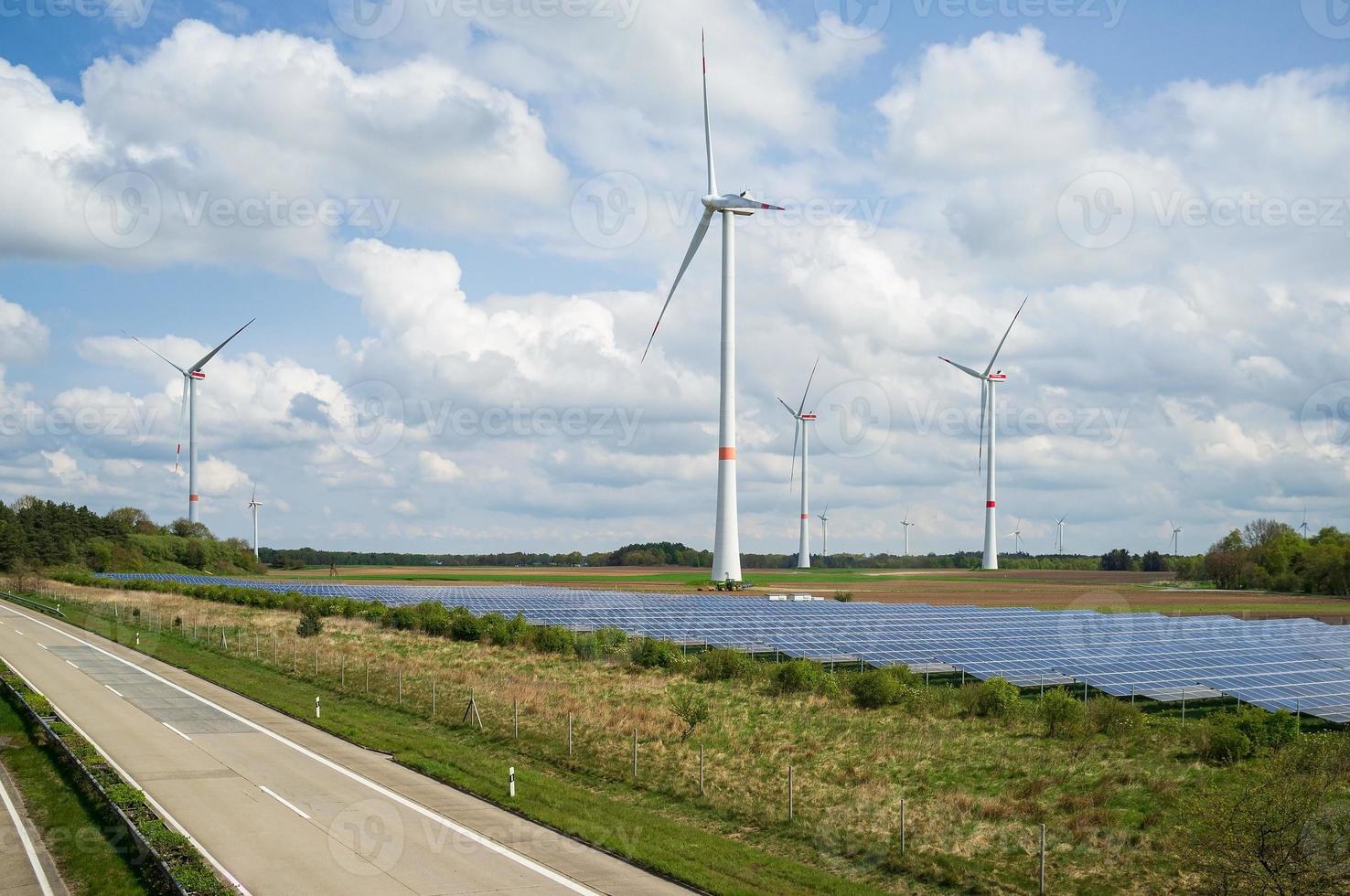 Farm with solar panels and wind turbines, located next to the highway, in the countryside. Green energy concept. photo