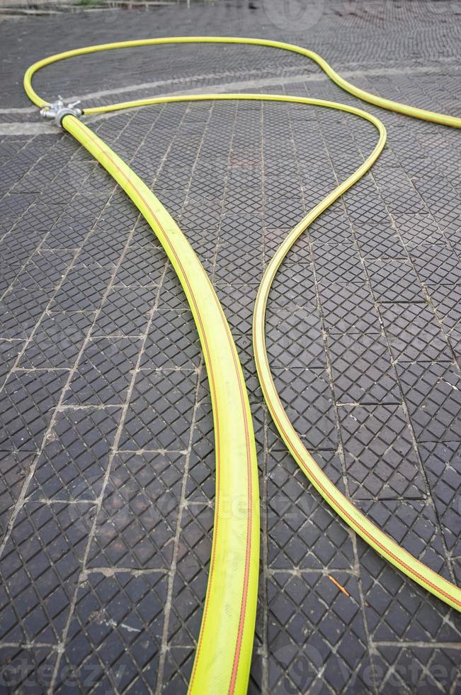 Yellow fire hose lies on a cobbled road, outdoors. Fire truck equipment. photo