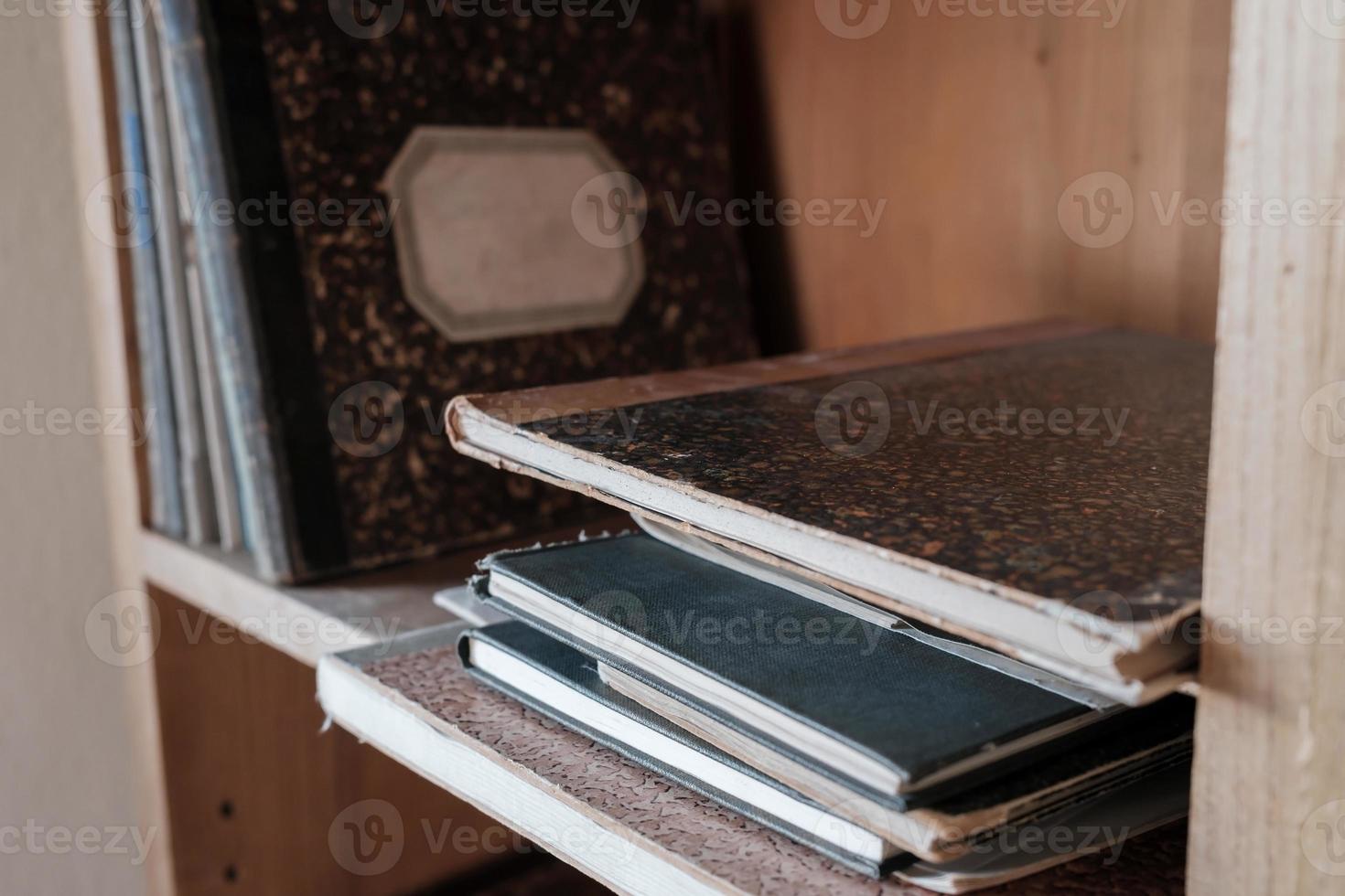 Paper notebooks in a hardcover, stacked and standing on a shelf. Close-up. photo