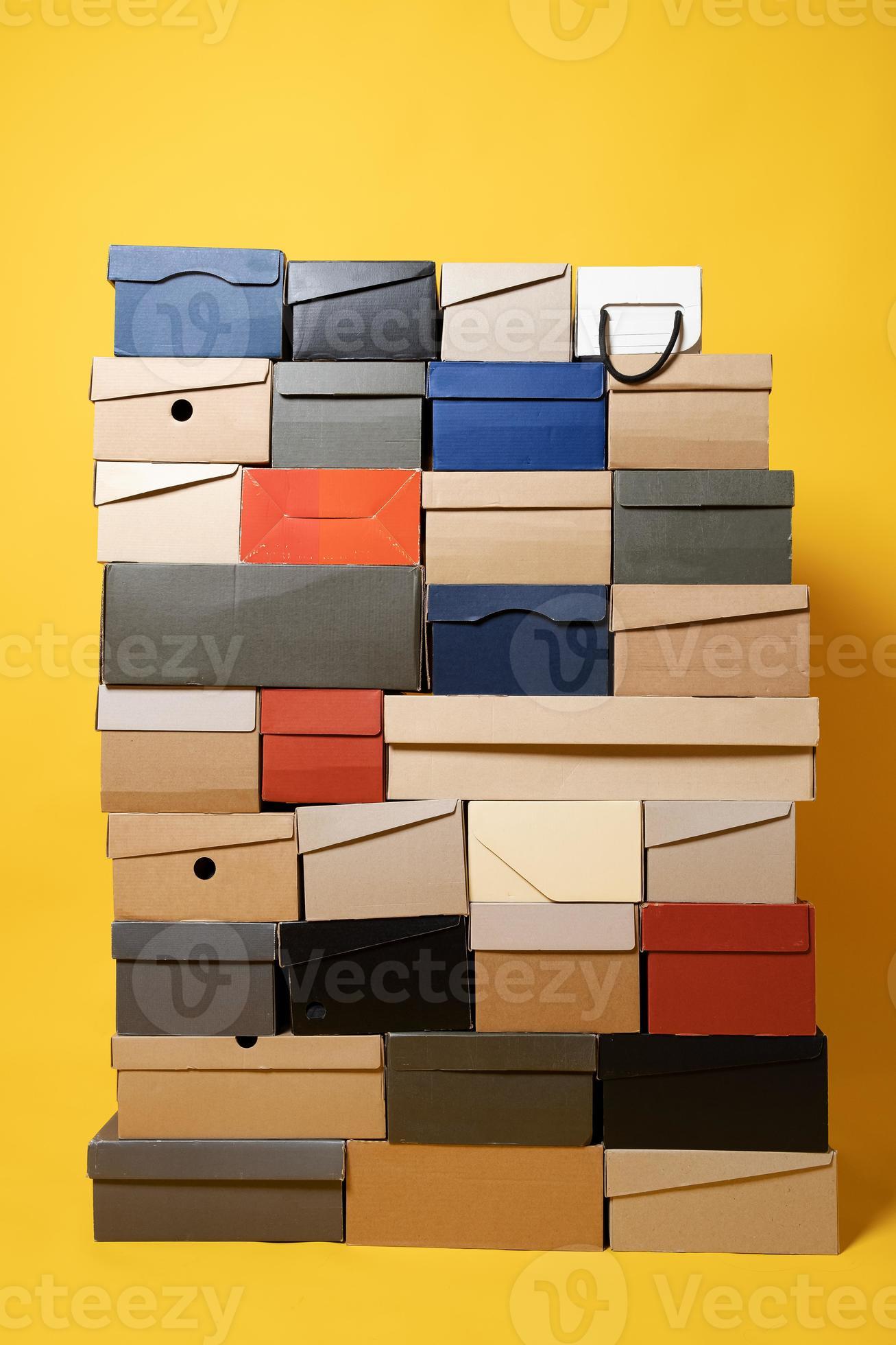 Various shoe boxes are stacked on a yellow background. Copy space. Sale