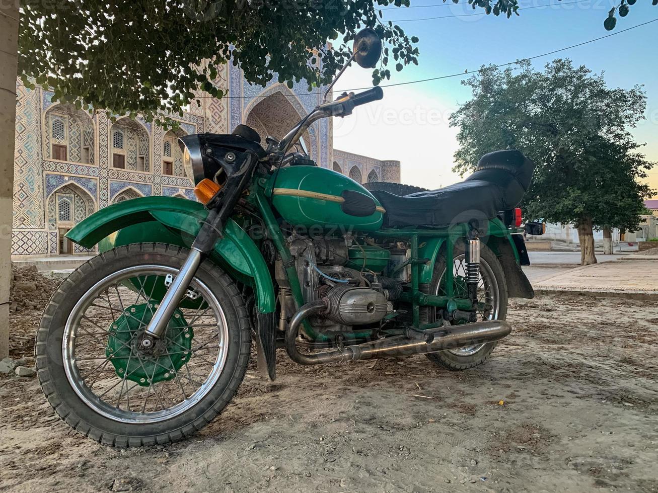 Motorcycle parked in front of a Qosh Mosque in Bukhara Uzbekistan photo