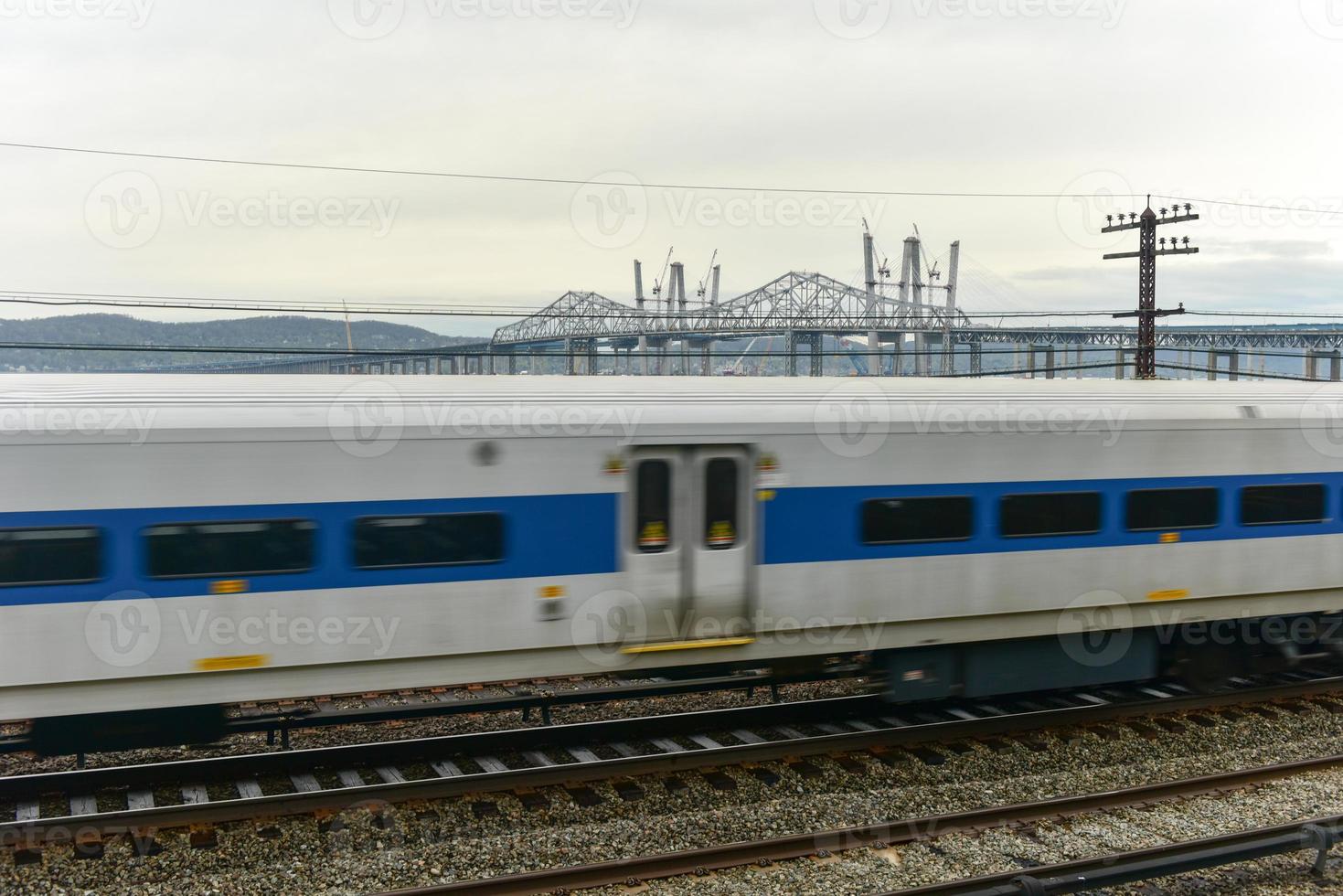 The new Tappan Zee bridge under construction across the Hudson River in New York across train tracks as a train passes by photo