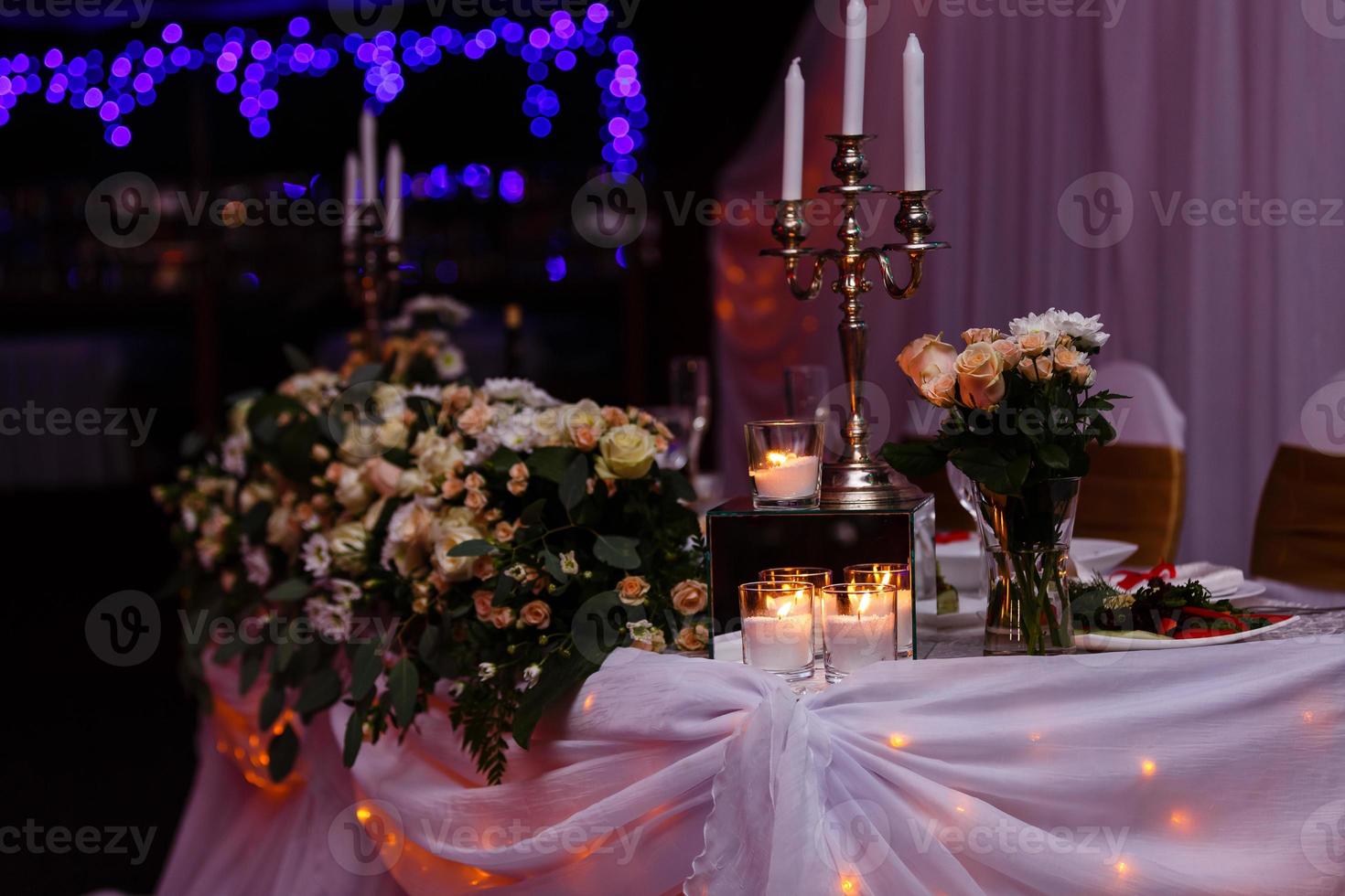 candelabro antiguo con ramo de boda. candelabro de boda con decoración floral antes de la ceremonia de boda. mesas preparadas para una recepción de boda foto