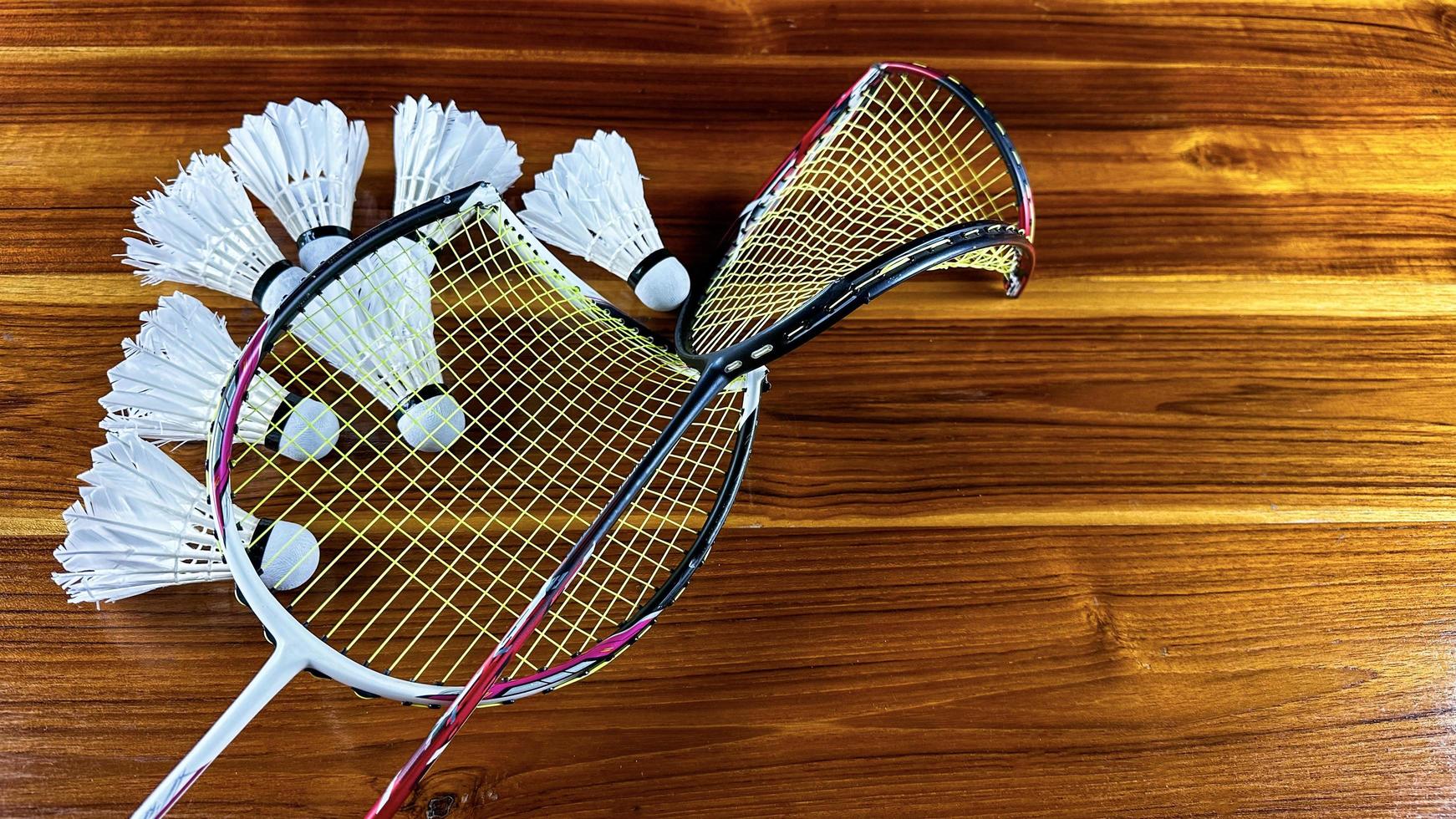 Close up of broken badminton rackets and white badminton shuttle cocks on brown wooden background photo