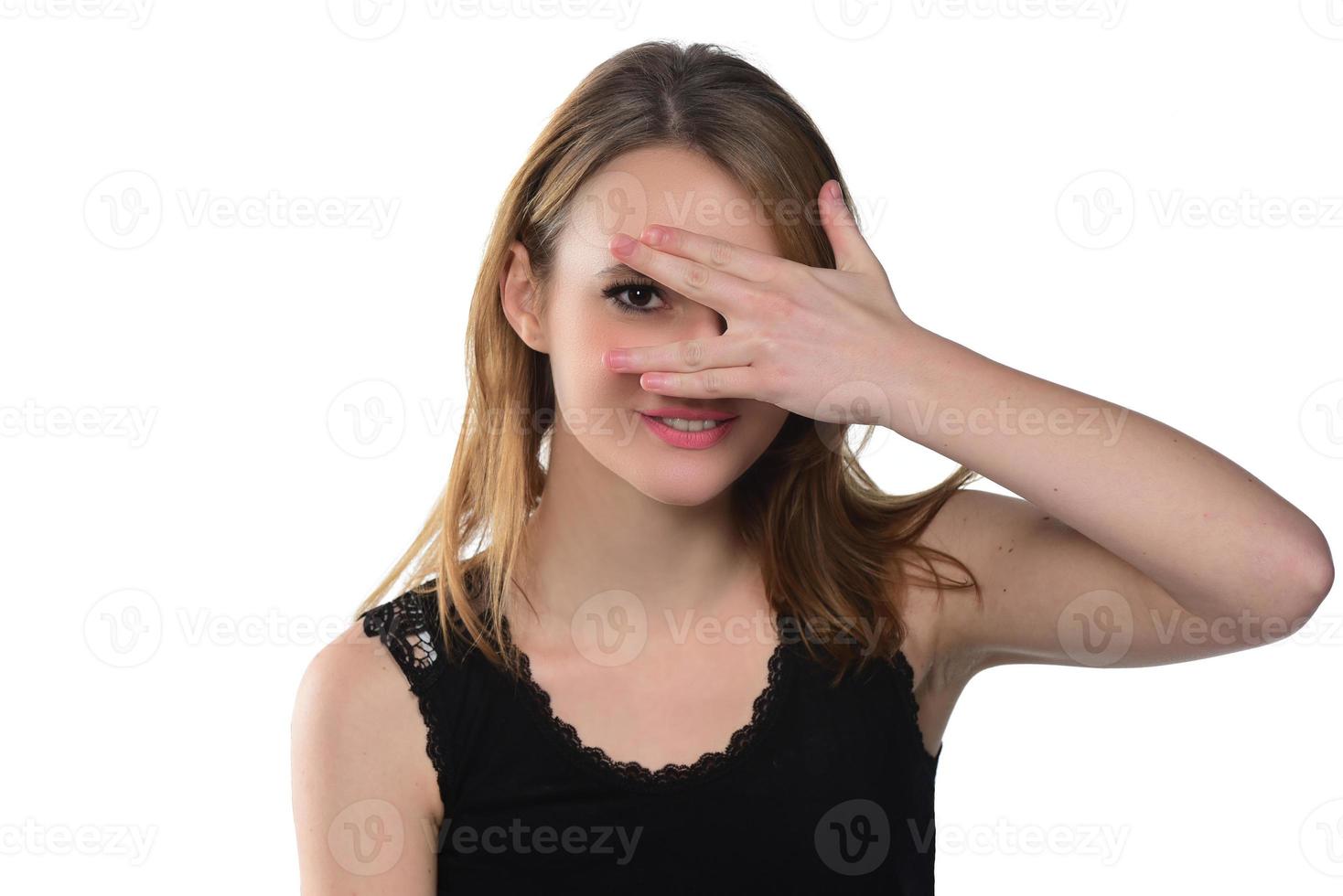 Portrait of young beautiful woman peeping at the camera through her fingers. Picture of embarrassed female looking through her hands covering her face isolated against home interior background photo