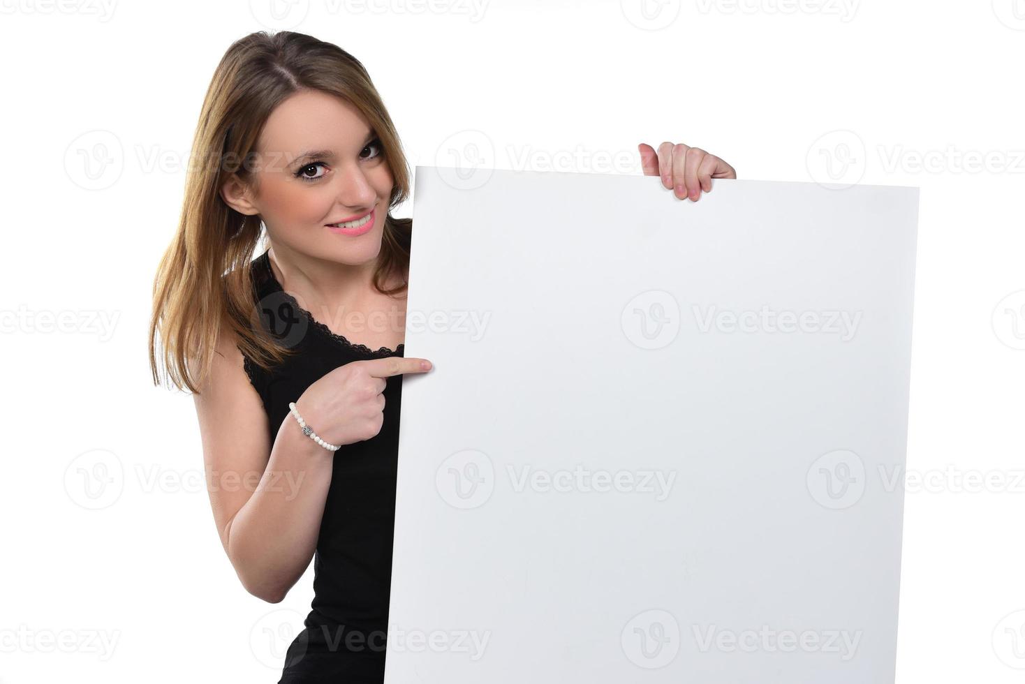 Portrait of young beautiful woman peeping at the camera holding white blank sign showing on it with finger.isolated on white photo