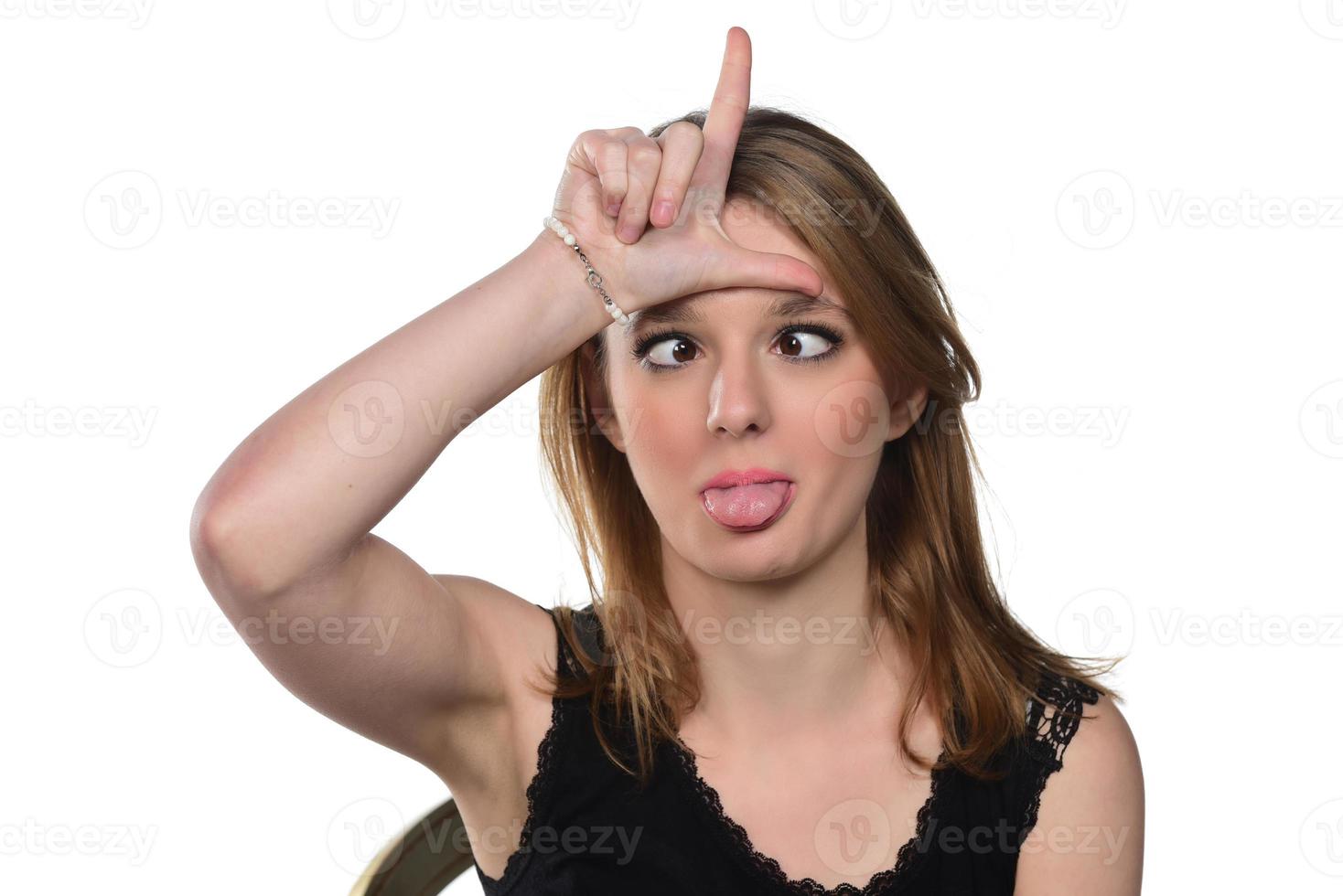 retrato de una joven hermosa mujer mirando a la cámara haciendo una cara graciosa y mostrando un signo de perdedor. aislado en blanco foto