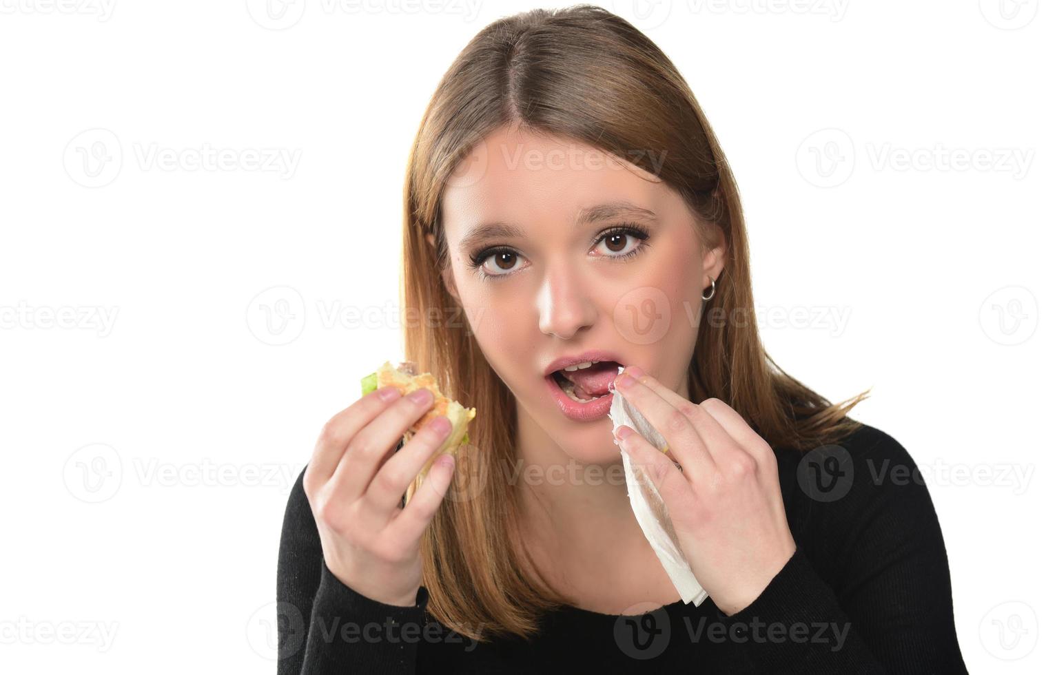 portrait of a beautiful funny young girl on the white background, blonde eating hamburger. Isolated photo