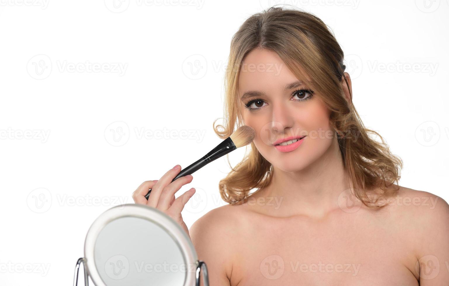 beautiful blond young smiling woman apply makeup with brush. isolated photo