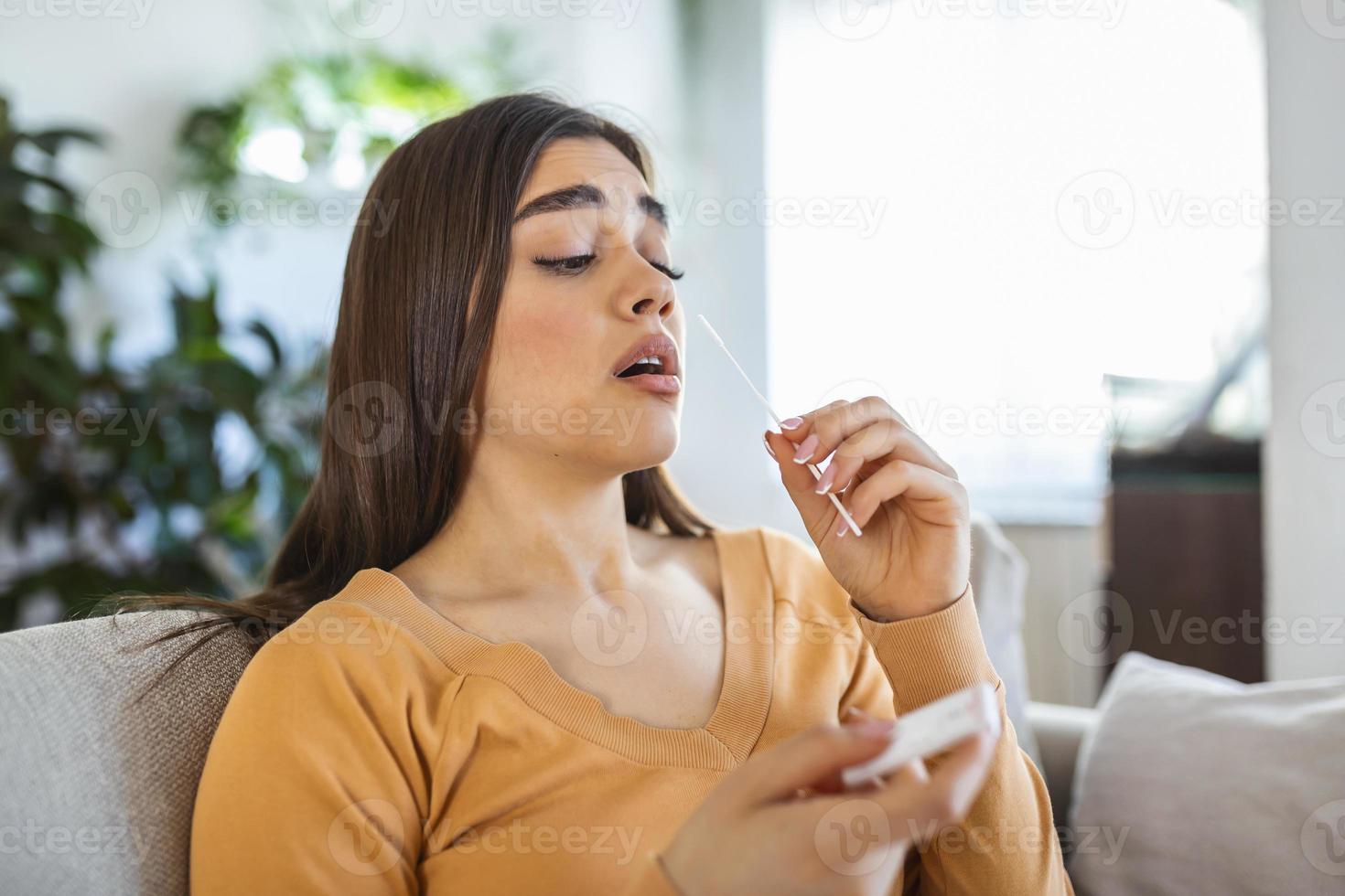 mujer joven sosteniendo un hisopo autoadministrado y un tubo médico para el coronavirus covid-19, antes de ser autoexaminado en casa foto