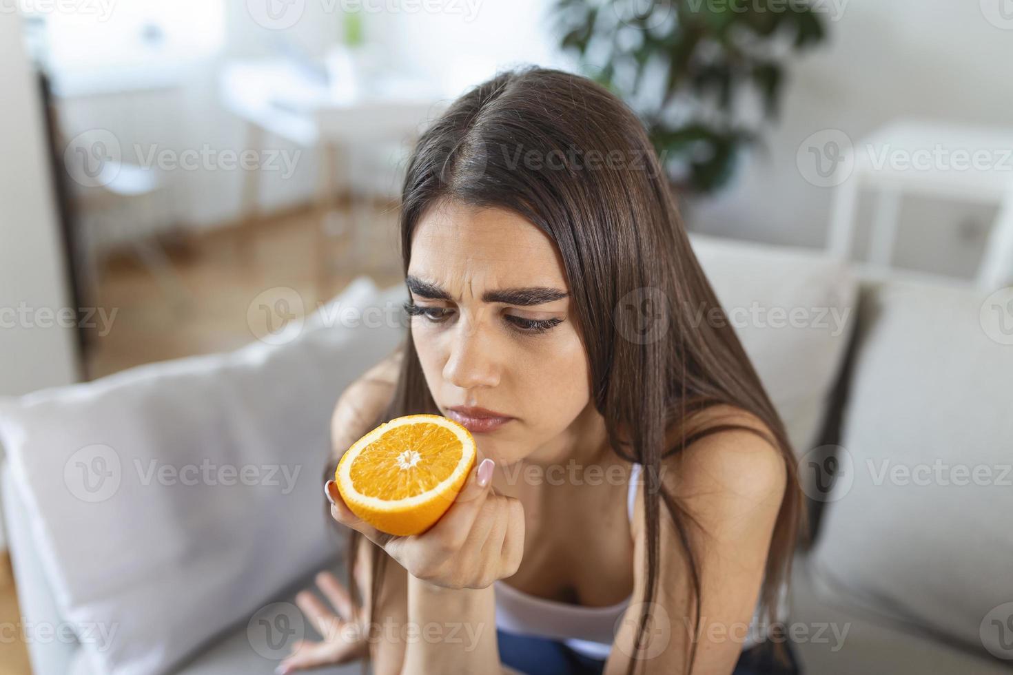 mujer enferma que intenta sentir el olor a media naranja fresca, tiene síntomas de covid-19, infección por el virus de la corona - pérdida del olfato y el gusto. uno de los principales signos de la enfermedad. foto