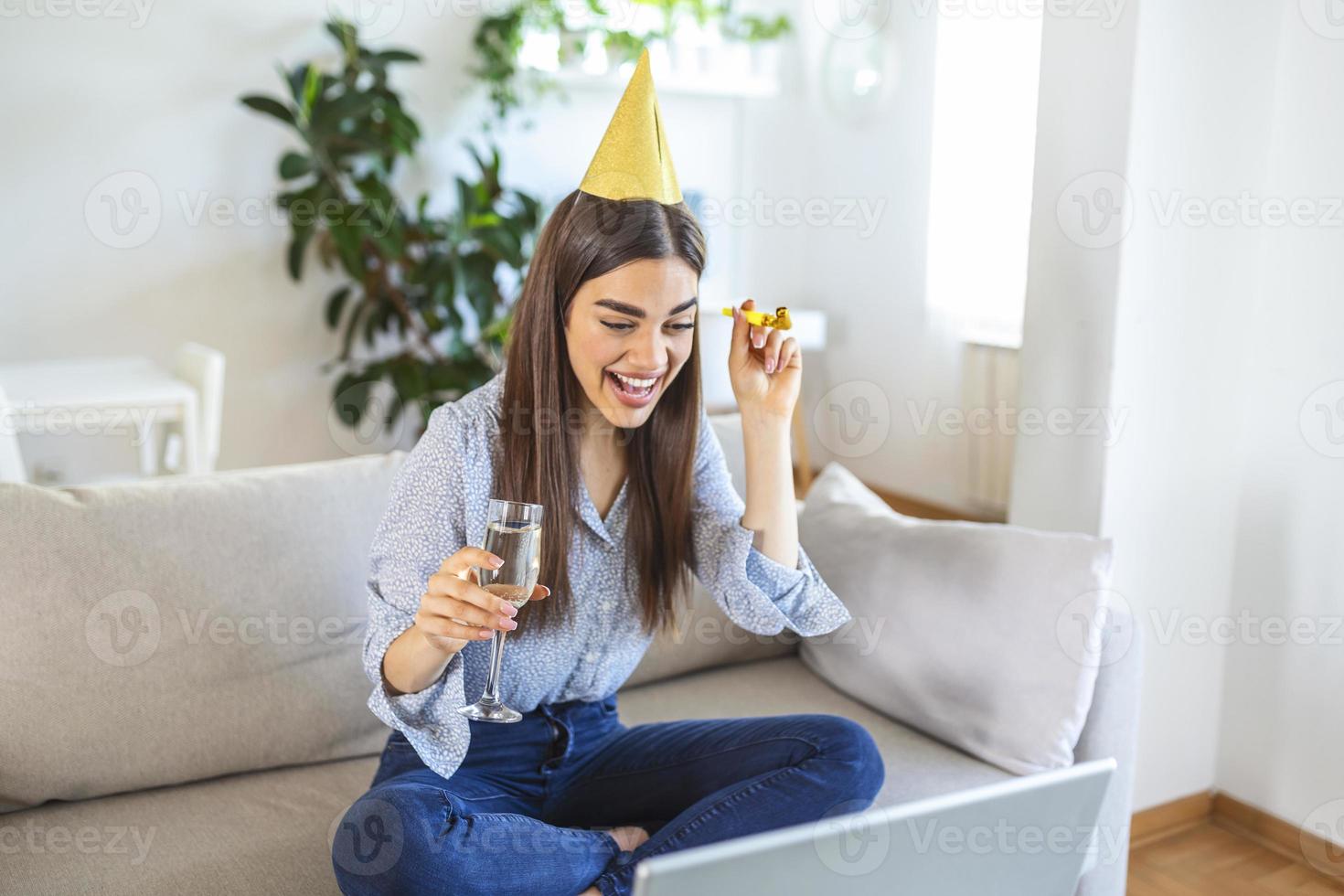 Virtual Party. Happy young woman in hat having video conference online meeting with friends and family, holding glass of wine, toasting and celebrating birthday, staying at home photo