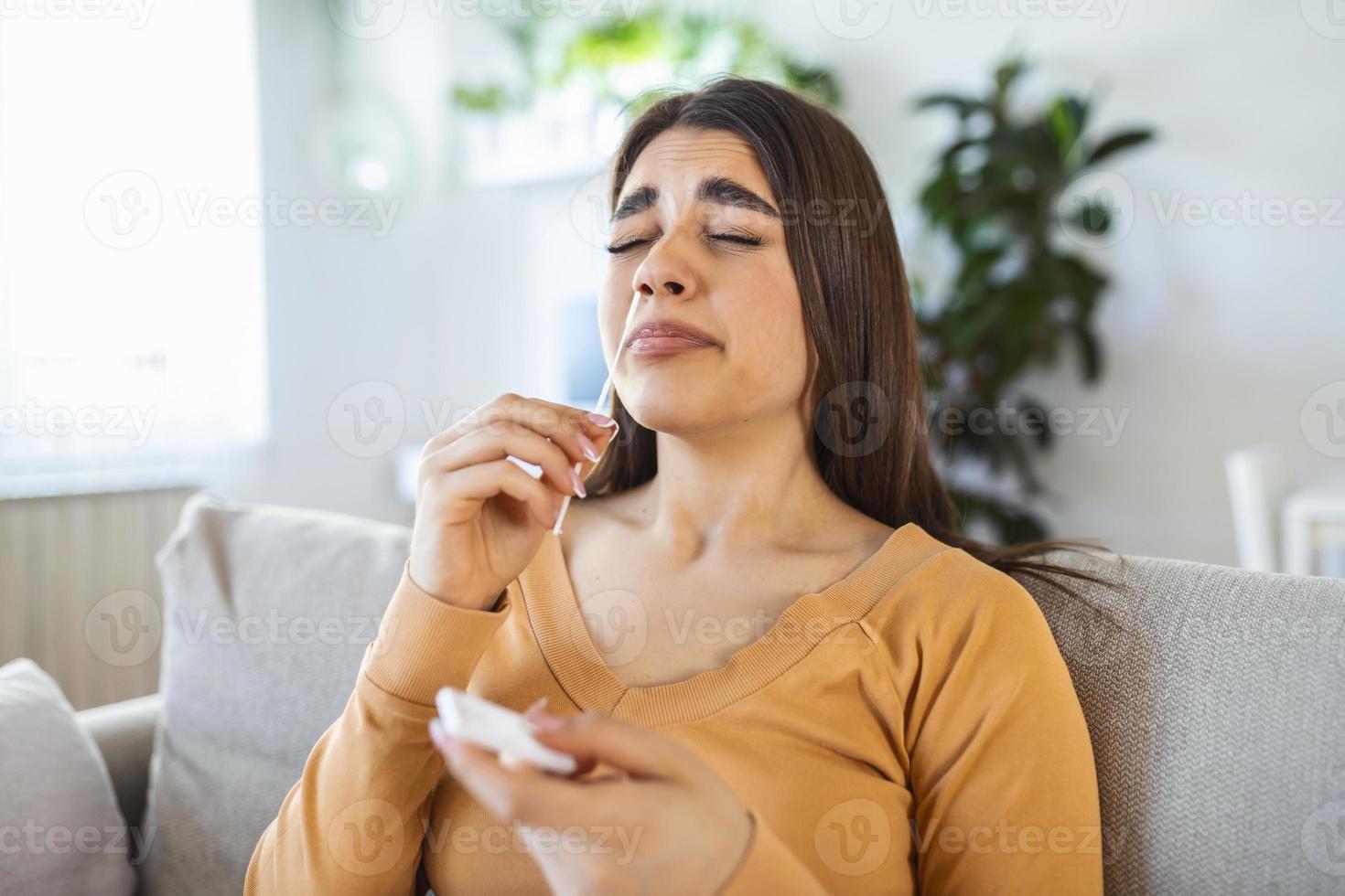 mujer joven sosteniendo un hisopo autoadministrado y un tubo médico para el coronavirus covid-19, antes de ser autoexaminado en casa foto