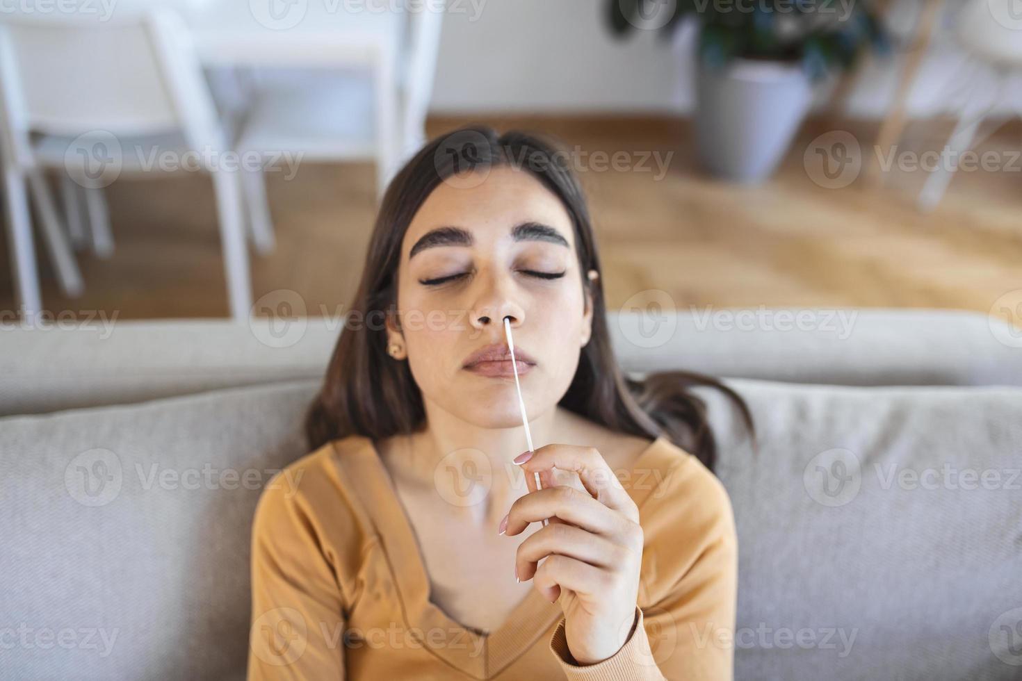 mujer joven sosteniendo un hisopo autoadministrado y un tubo médico para el coronavirus covid-19, antes de ser autoexaminado en casa foto