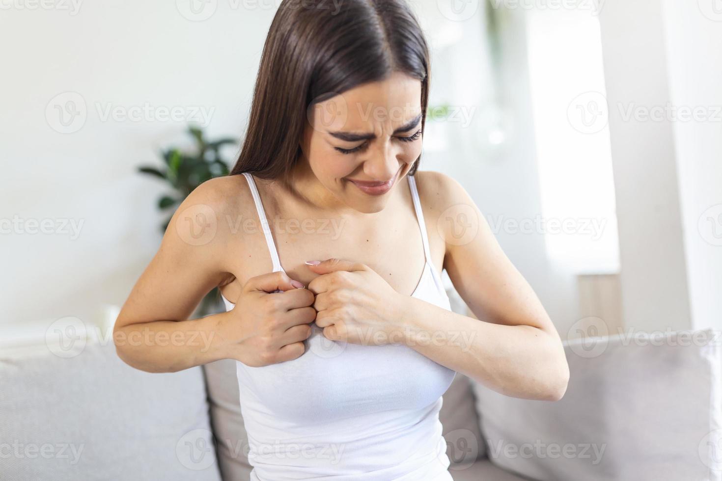 mujer sentada con fuerte dolor de pecho y manos tocándose el pecho mientras tiene problemas en casa, ataque al corazón o síntoma de insuficiencia cardíaca foto