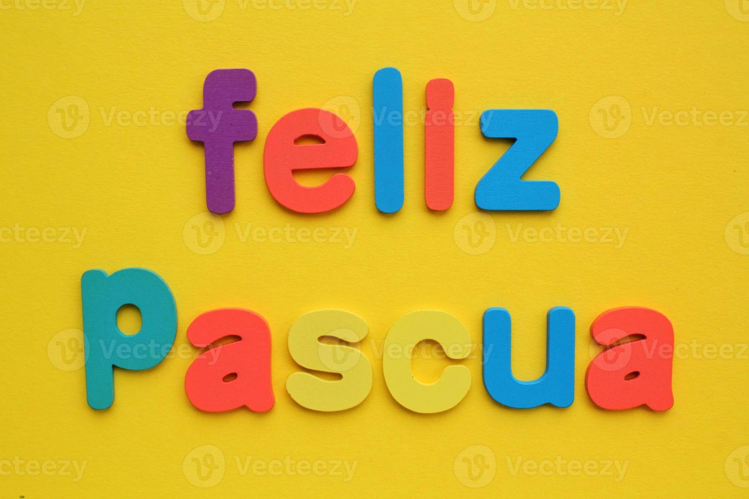 Feliz Pascua, Happy Easter on spanish colored lettering on yellow background. Holiday spring compostion concept. Creative idea for greeting card, poster, banner, invitation. Top view, flat lay photo