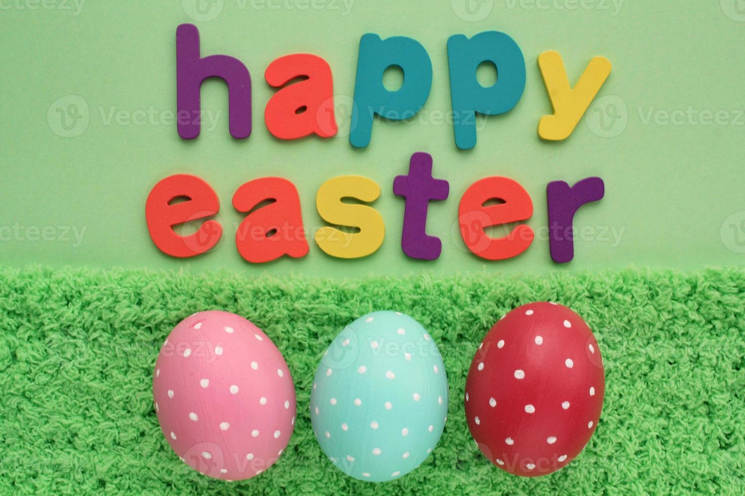 Happy Easter letters on green background and coloured eggs with polka dot on spring grass background. Greeting card, invitation, banner, poster sale. Flatlay, top view. Composition holiday concept photo