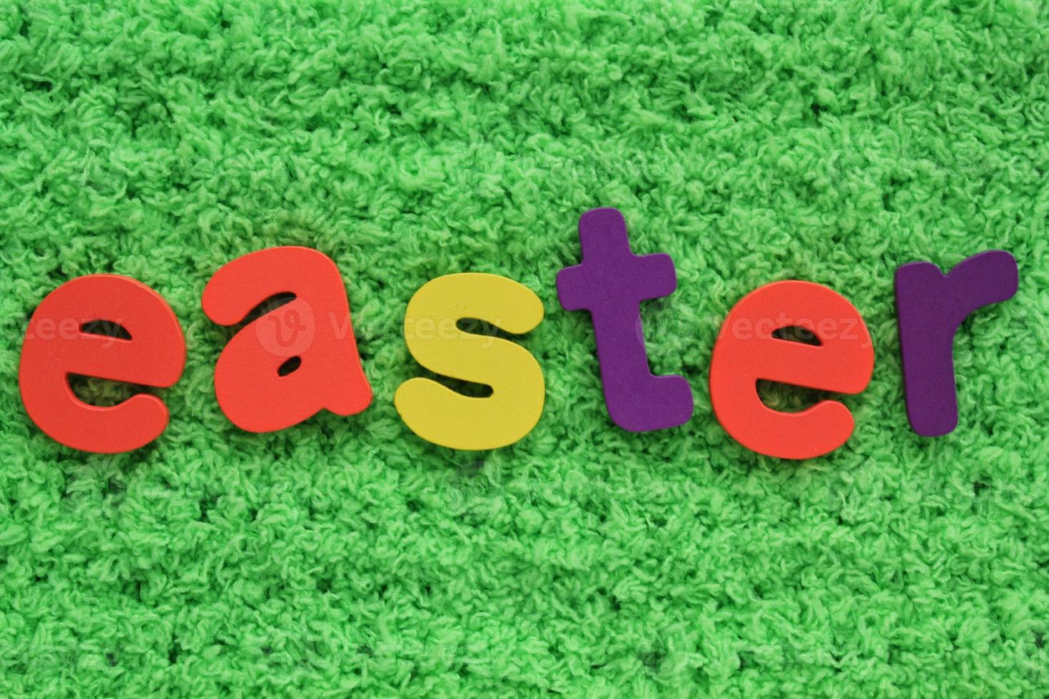 Easter colored lettering on green grass background. Holiday spring composition concept. Creative idea for greeting card, poster, banner, invitation, web. Top view, flat lay, close up photo