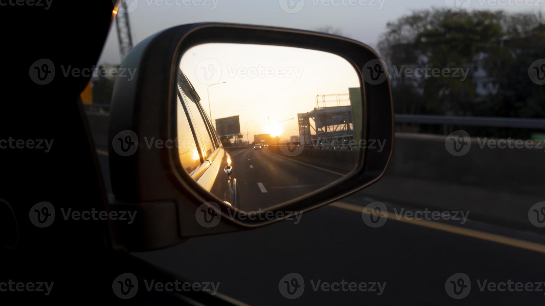 Wing mirror view of car on the asphalt road. With reflections of other cars lining the back in traffic. Environment in the evening or morning time. photo