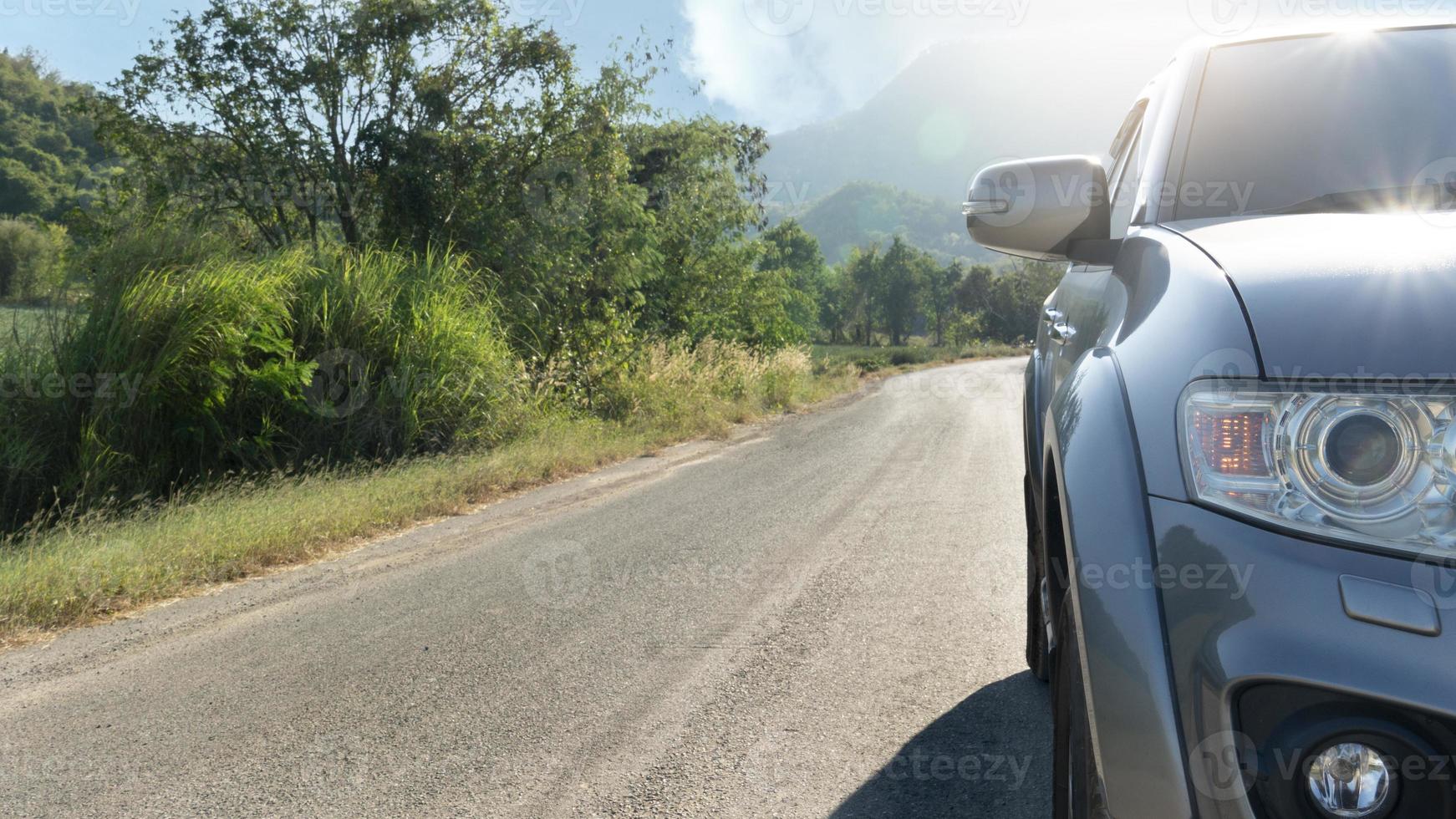 Front view of car running on the asphalt road for travel trip. With nature of trees and grass beside road. Under the blue sky. photo