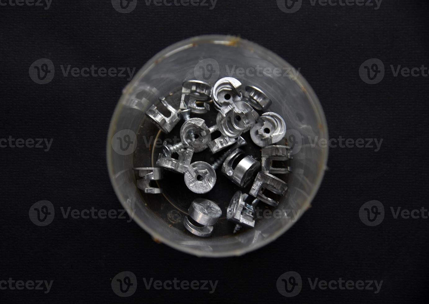 Construction bolts and screws in plastic cups on a black background. Construction accessories. photo
