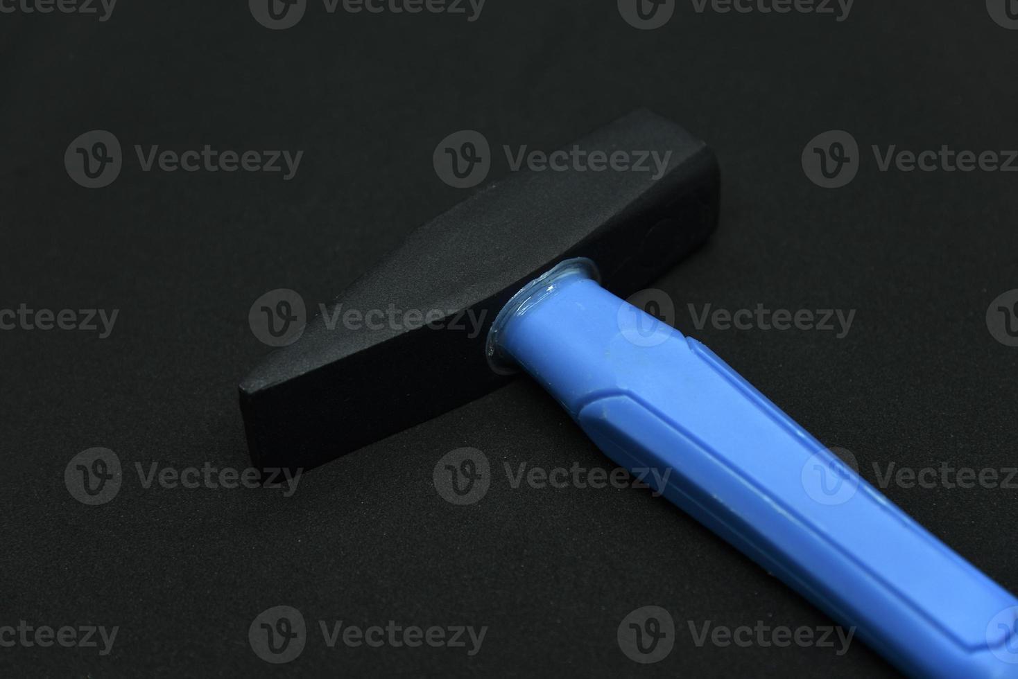 Construction hammer on a black background. A carpenter's hammer with a blue handle on a black background. photo