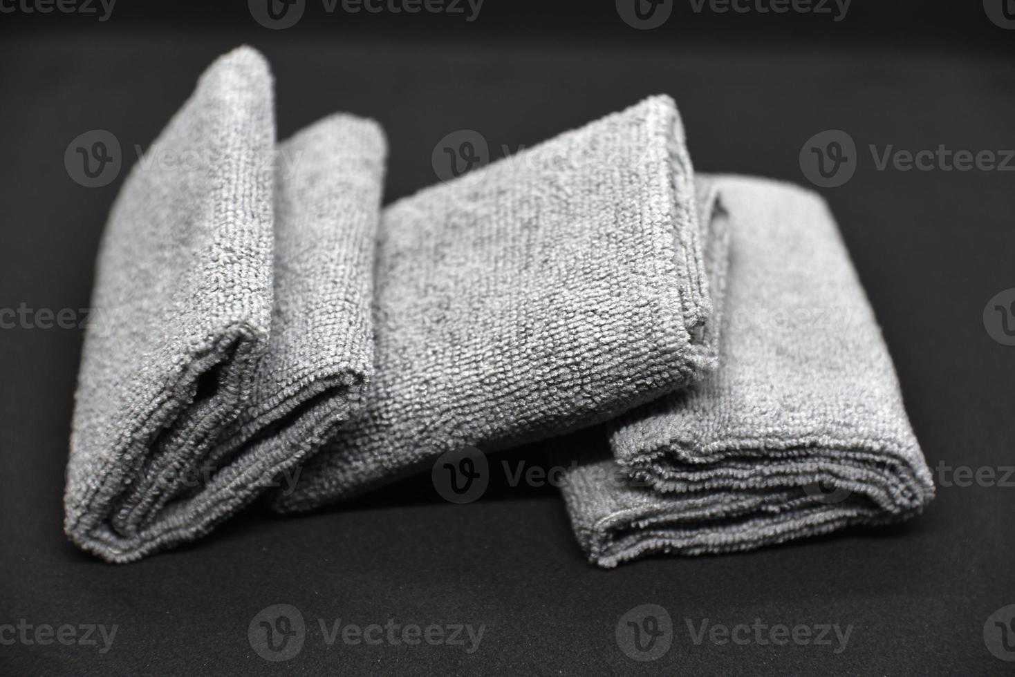 Three gray towels on a black background. Terry cloths for wiping furniture. Towels on a black background. photo