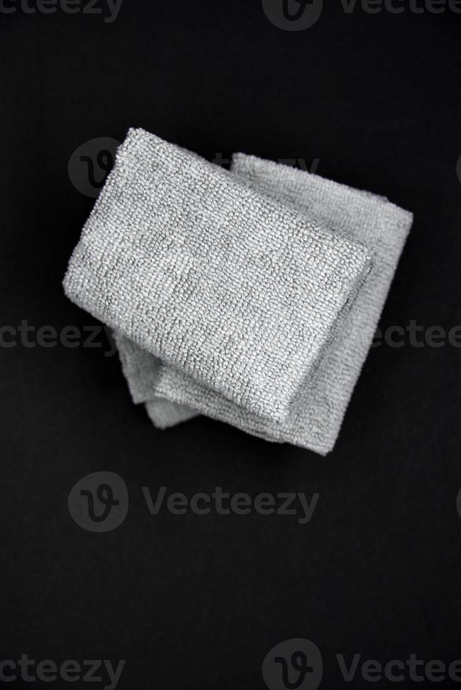 Three gray towels on a black background. Terry cloths for wiping furniture. Towels on a black background. photo