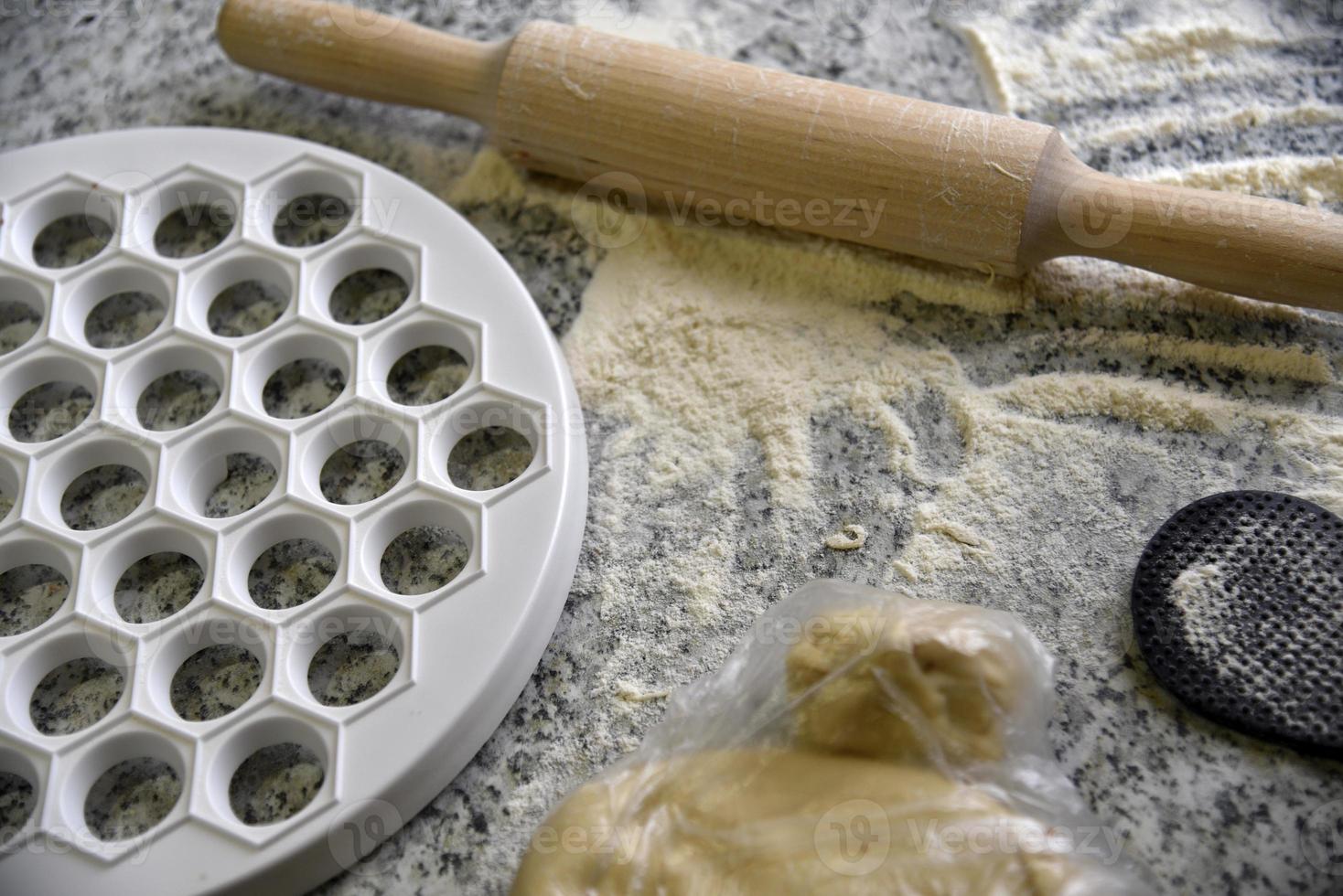 A mold for modeling dumplings. Dough for dumplings. Rolling pin. photo